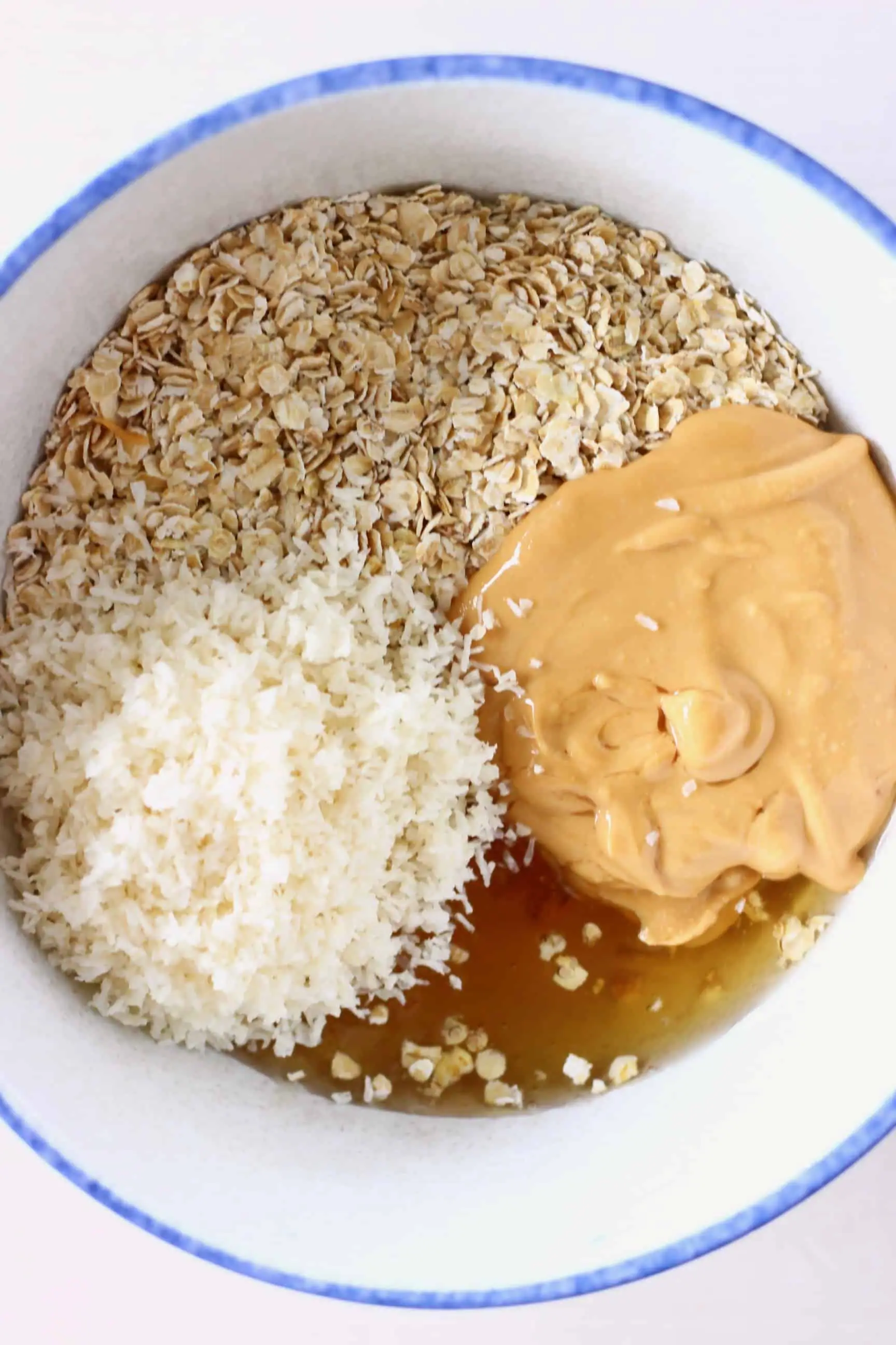 Oats, desiccated coconut, peanut butter and agave syrup in a bowl