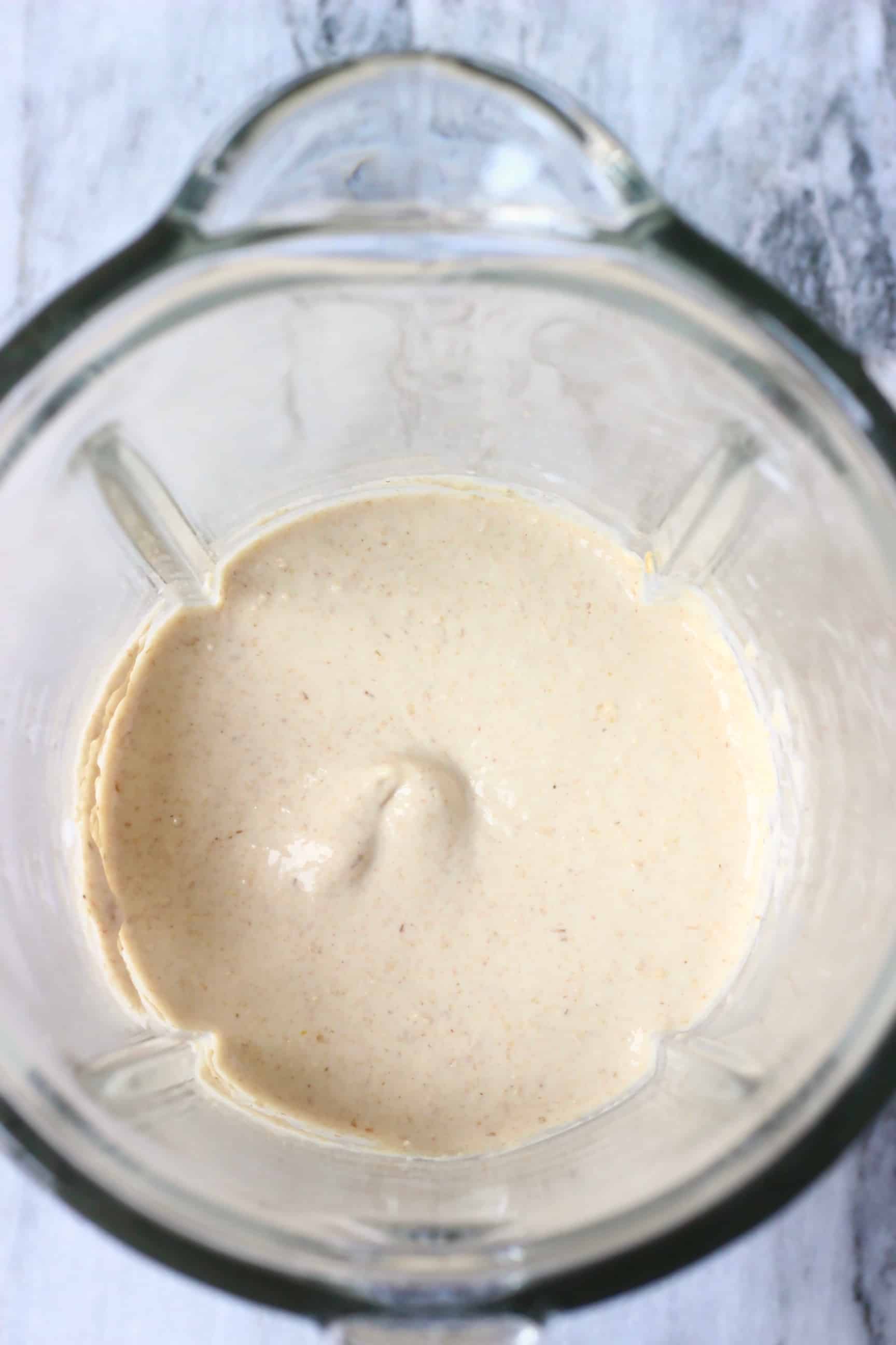 Raw banana oatmeal pancake batter in a glass blender against a marble background
