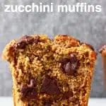 A zucchini muffin with chocolate chips cut in half on a marble slab against a grey background