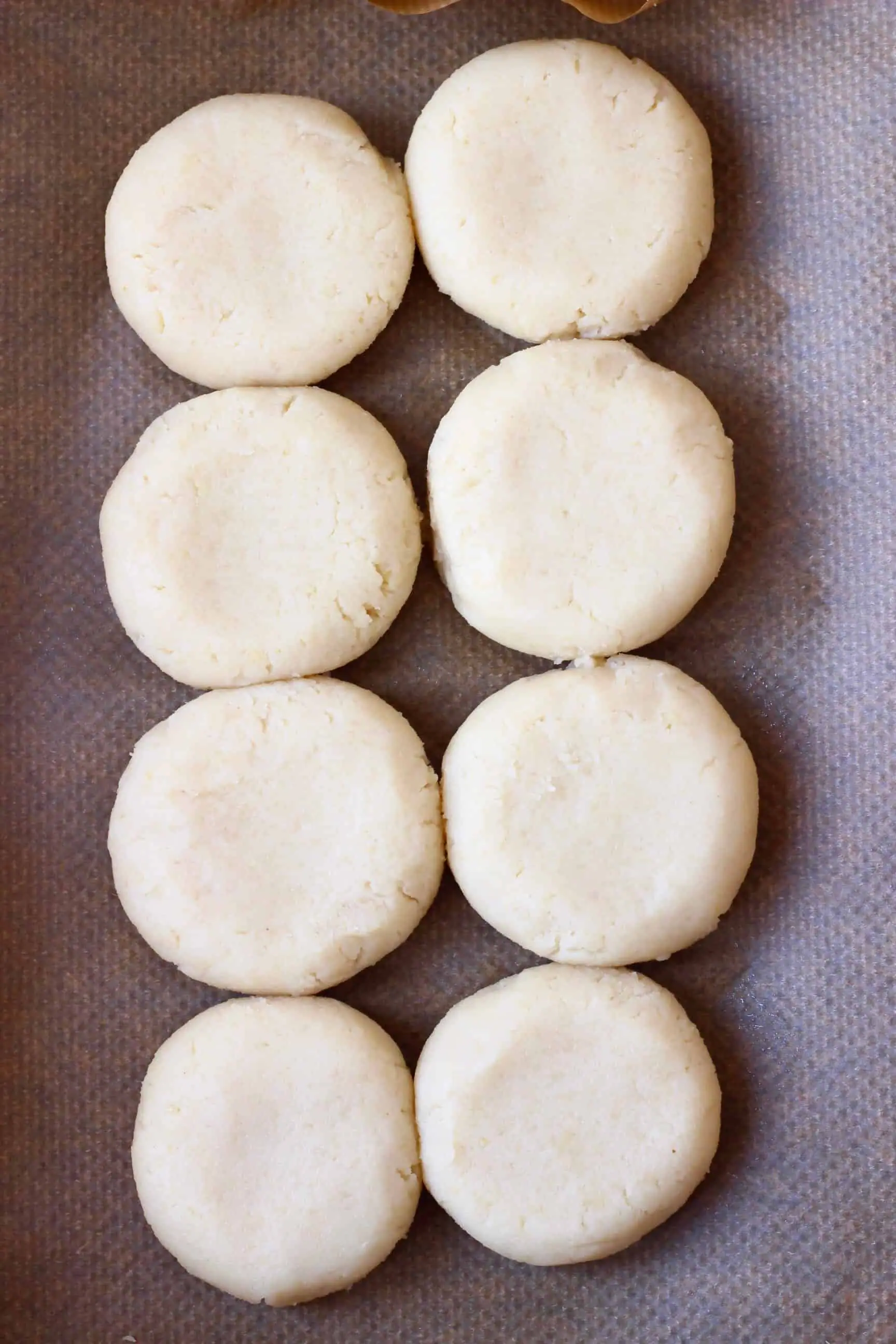 Eight raw gluten-free vegan shortcakes on a sheet of baking paper