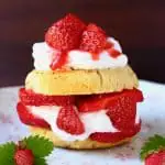 A gluten-free vegan strawberry shortcake sandwiched with coconut whipped cream and fresh strawberries on a plate