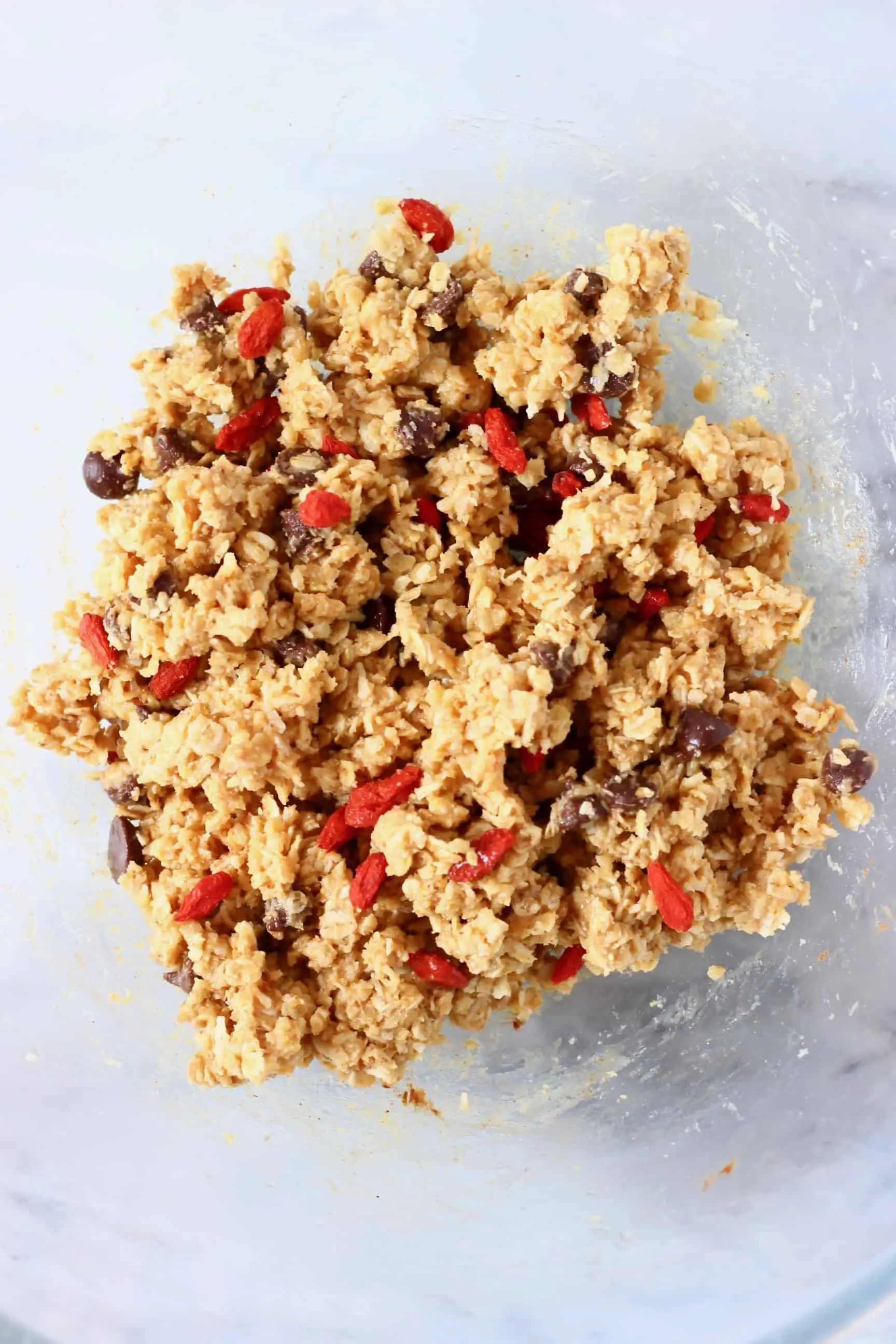 No-bake granola bar mixture with goji berries and chocolate chips in a bowl