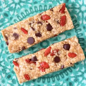 Two no-bake granola bars with chocolate chips and goji berries on a plate