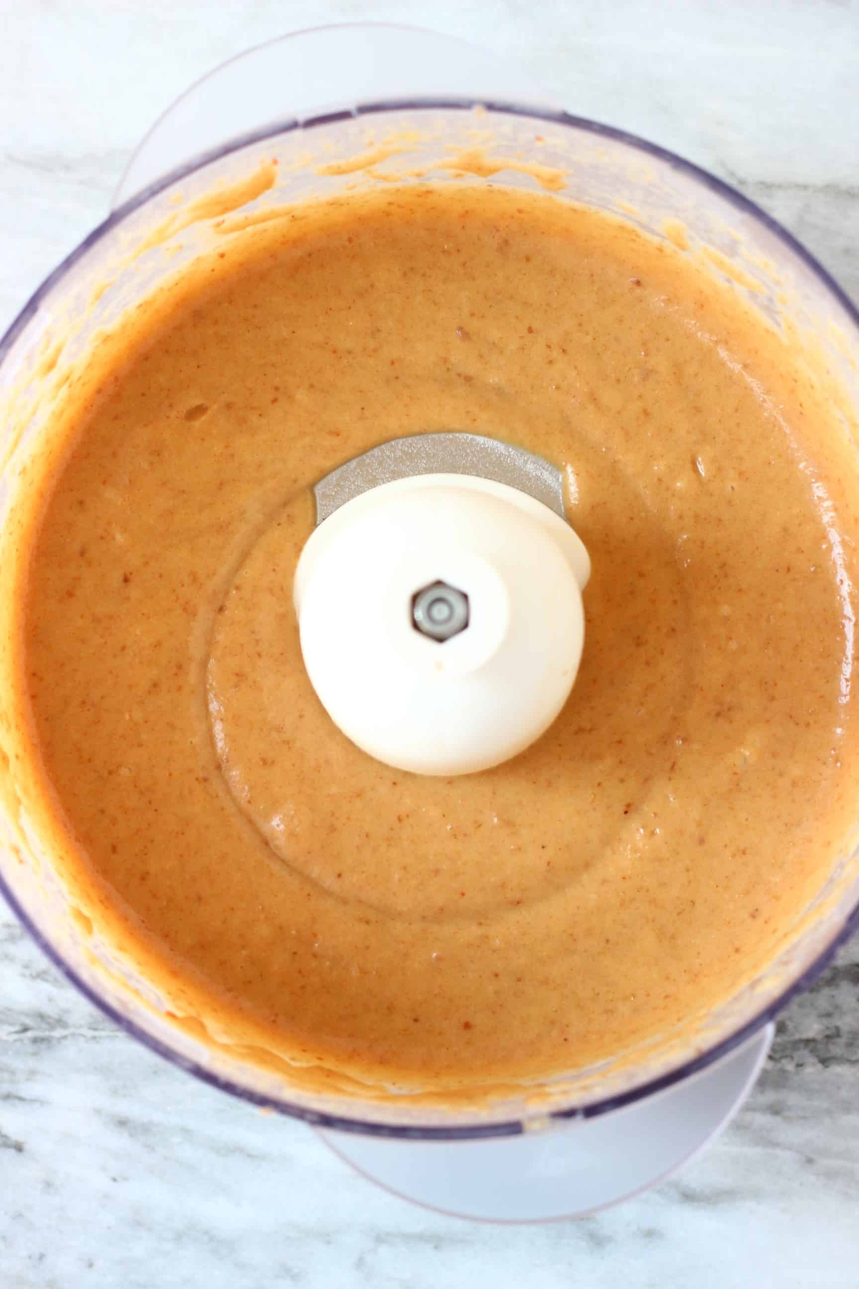 A brown purée in a food processor against a marble background