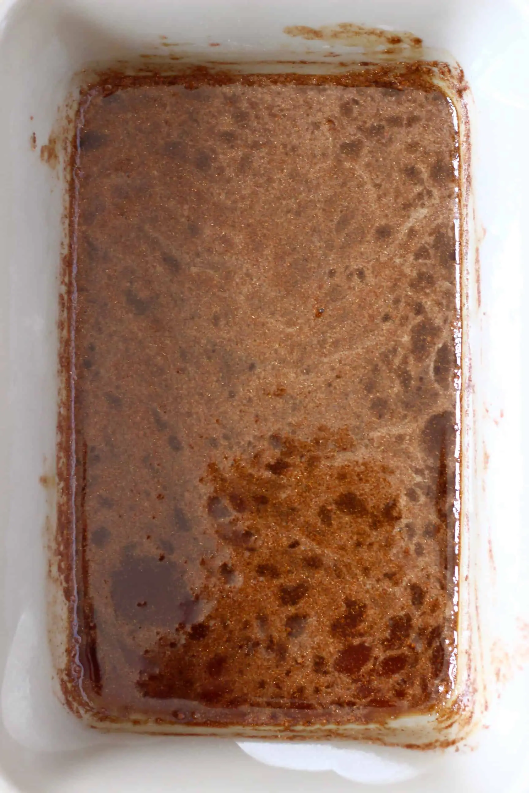 Dark brown caramel sauce for baked apples in a rectangular baking dish