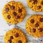 Five pumpkin cookies with chocolate chips against a marble background