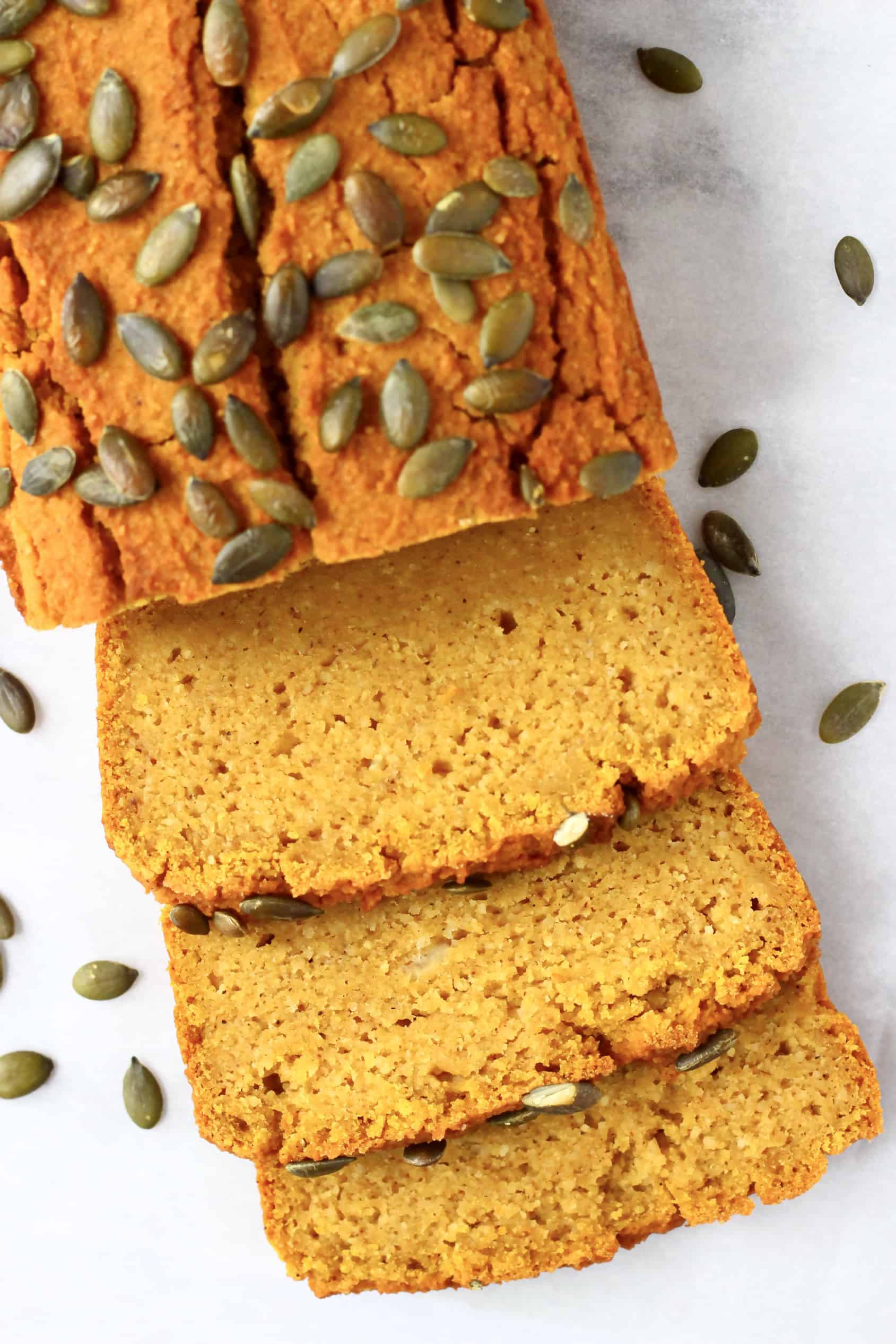 A loaf of gluten-free vegan pumpkin bread with three slices next to it