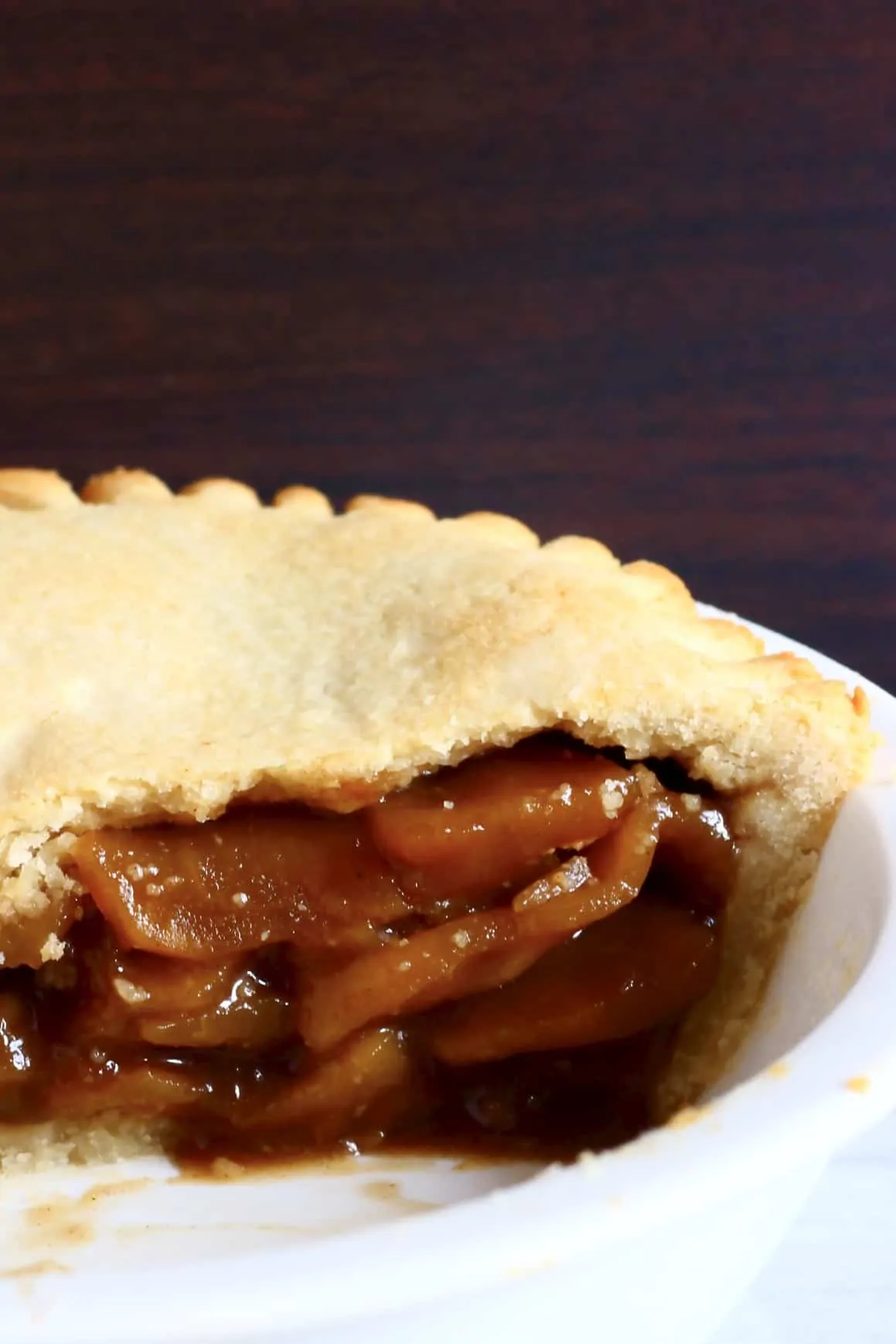 A sliced gluten-free vegan apple pie in a white pie dish