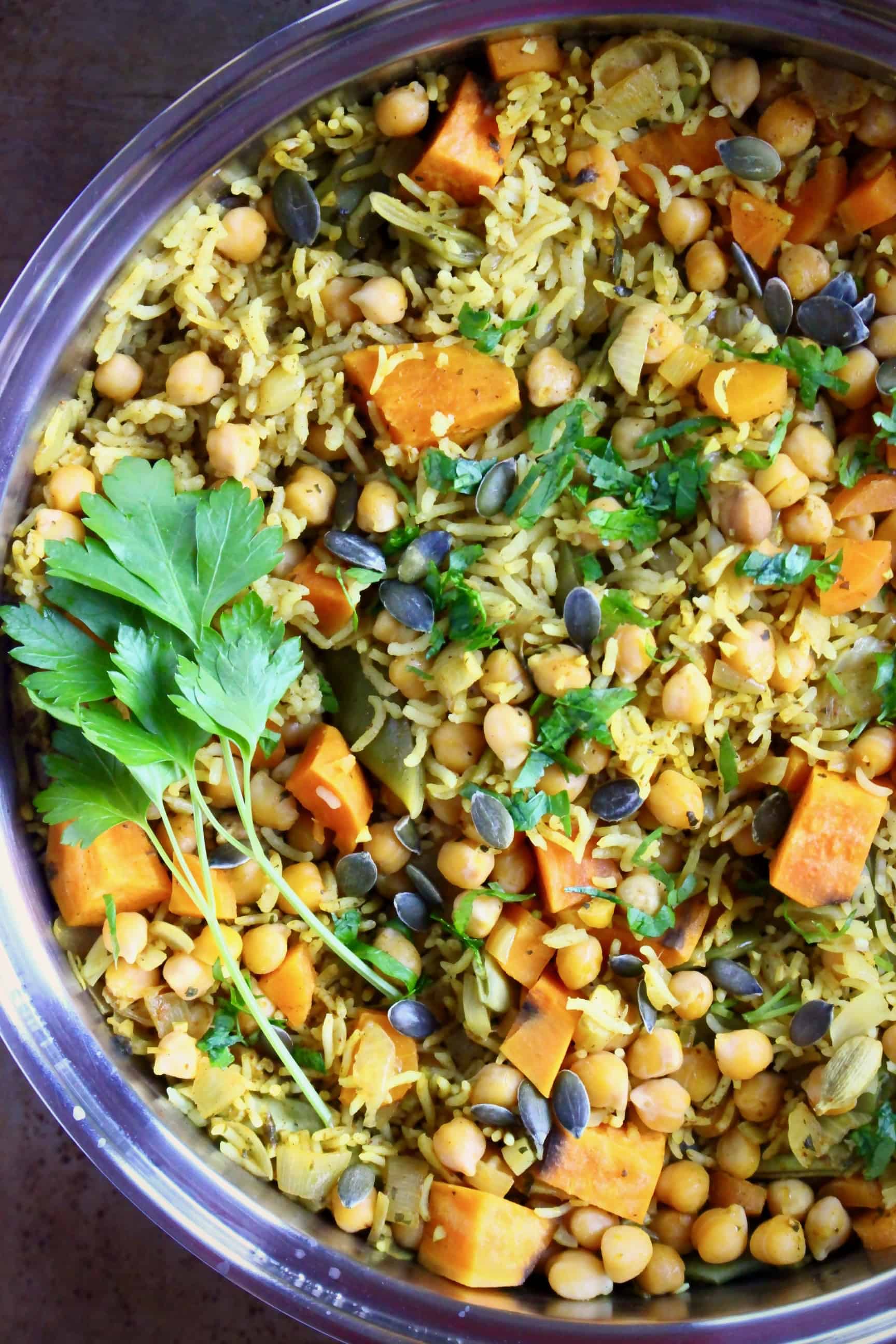 Yellow biryani rice with chopped pumpkin, chickpeas and pumpkin seeds in a silver saucepan