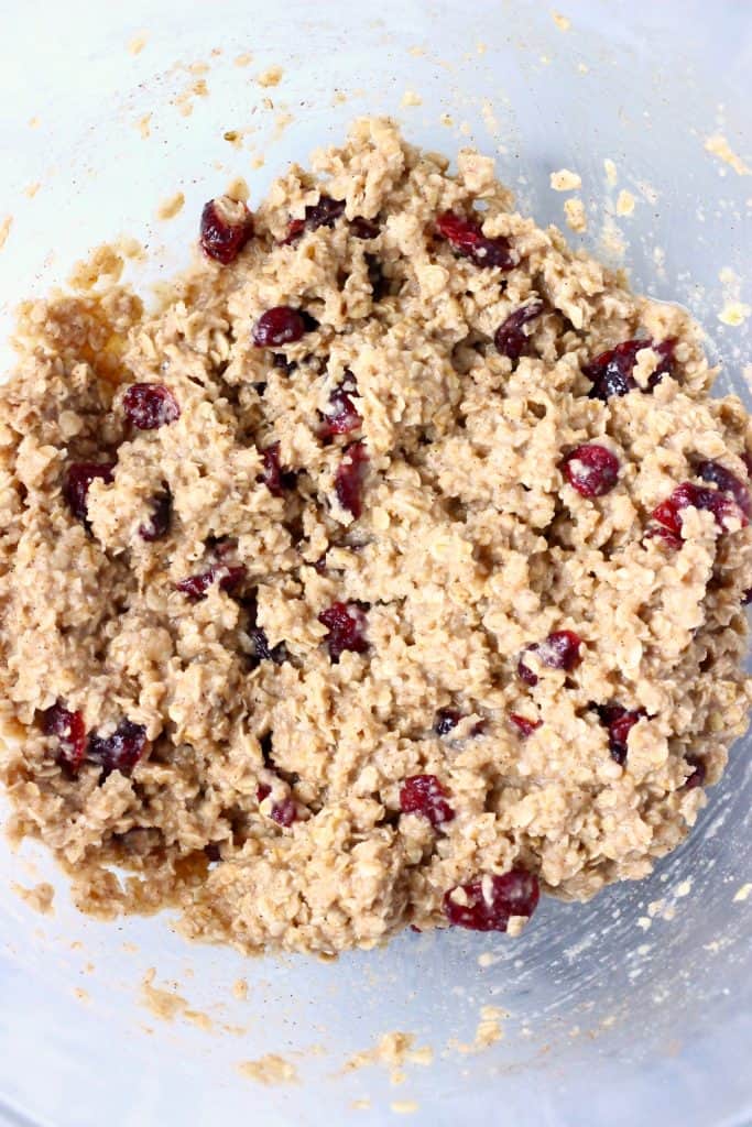 A glass bowl of raw oatmeal cookie dough with dried cranberries