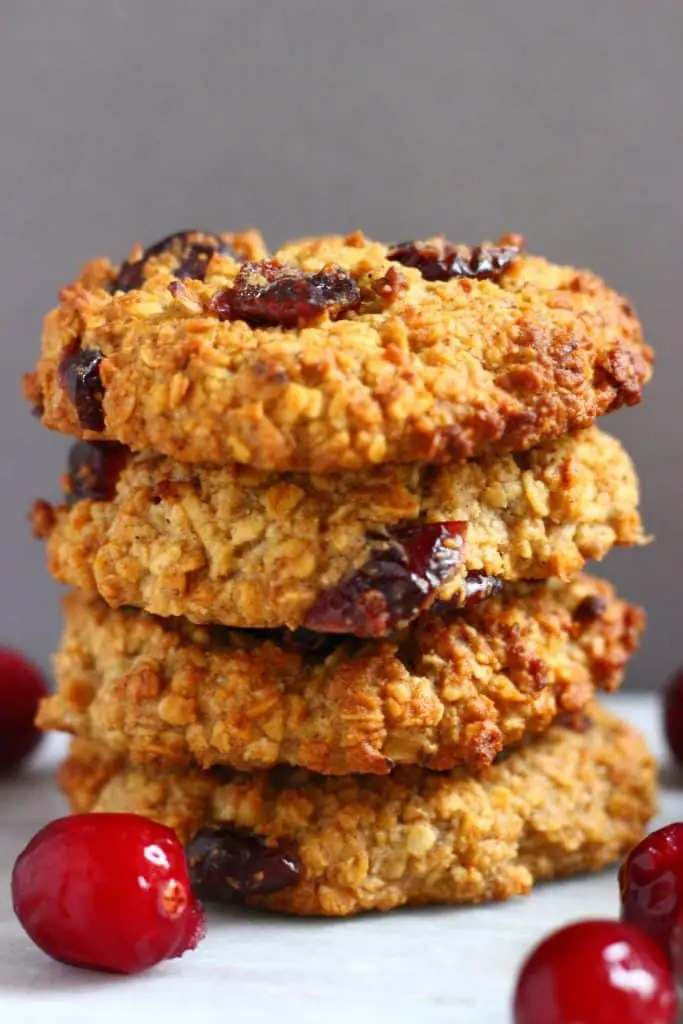 A stack of four oatmeal cookies with dried cranberries against a grey background