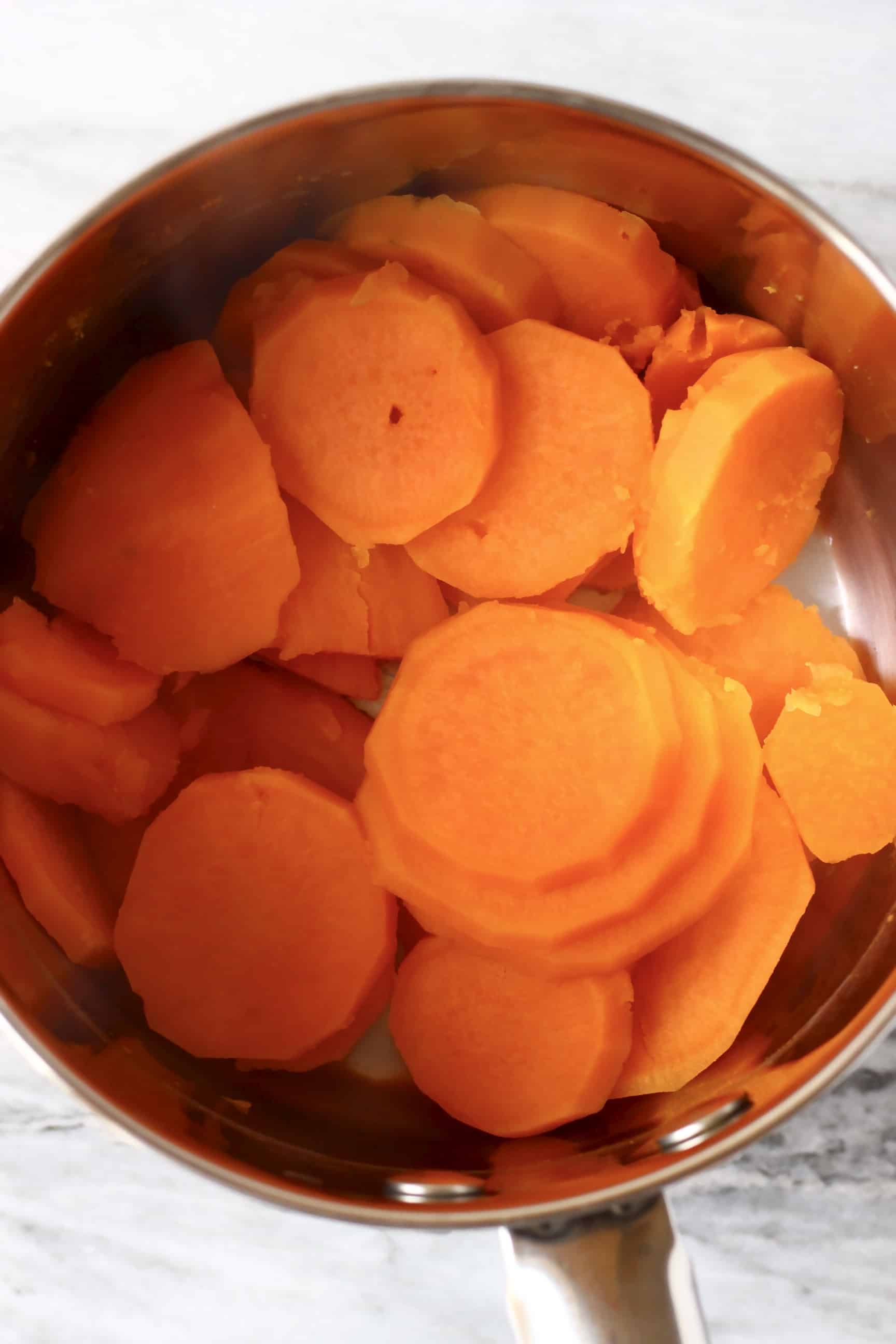 Sliced cooked sweet potatoes in a silver pan