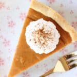 A slice of vegan sweet potato pie topped with cream on a plate with a fork