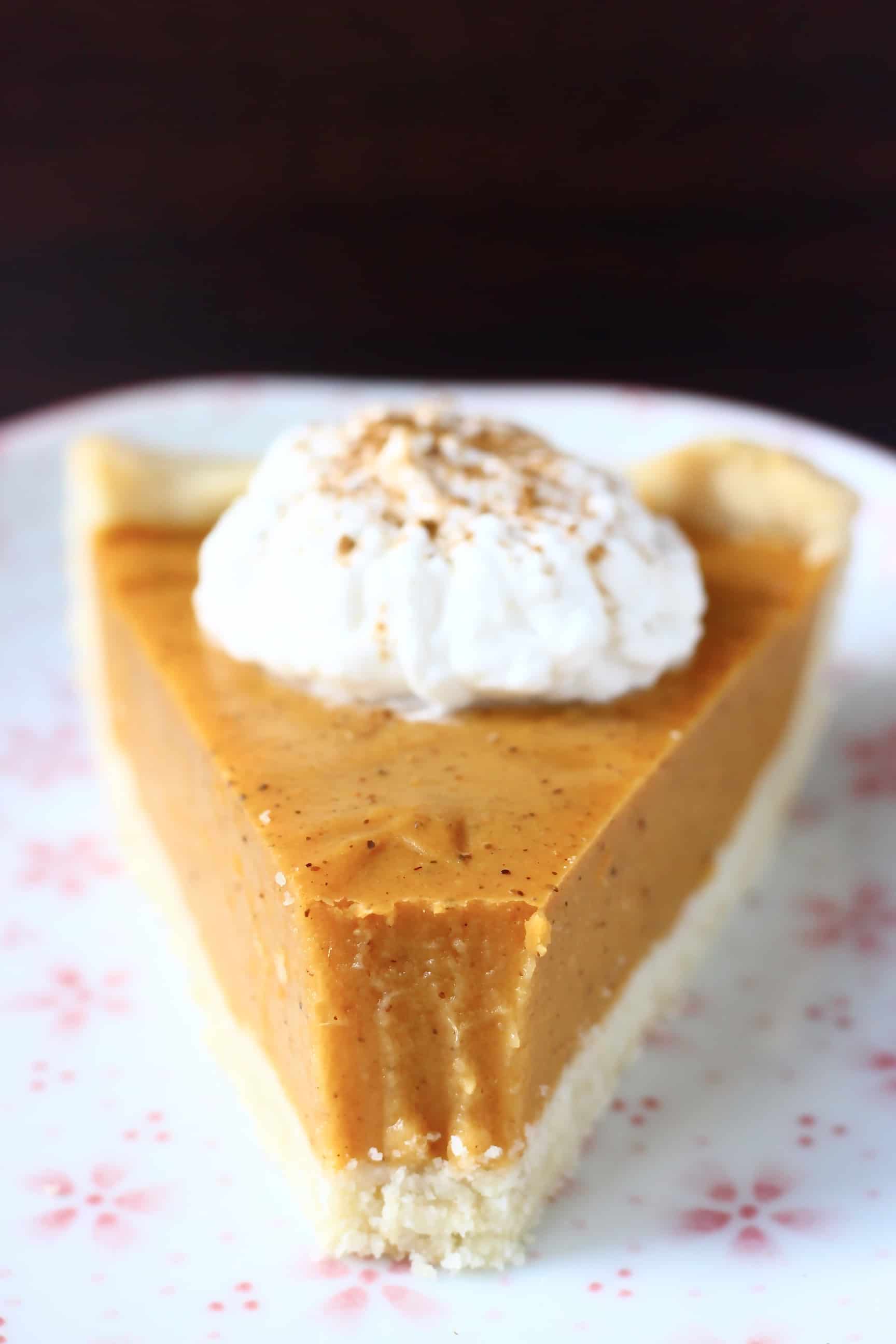A slice of vegan sweet potato pie topped with cream with a bite taken out of the end