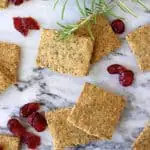 Several square gluten-free vegan crackers with dried cranberries and rosemary