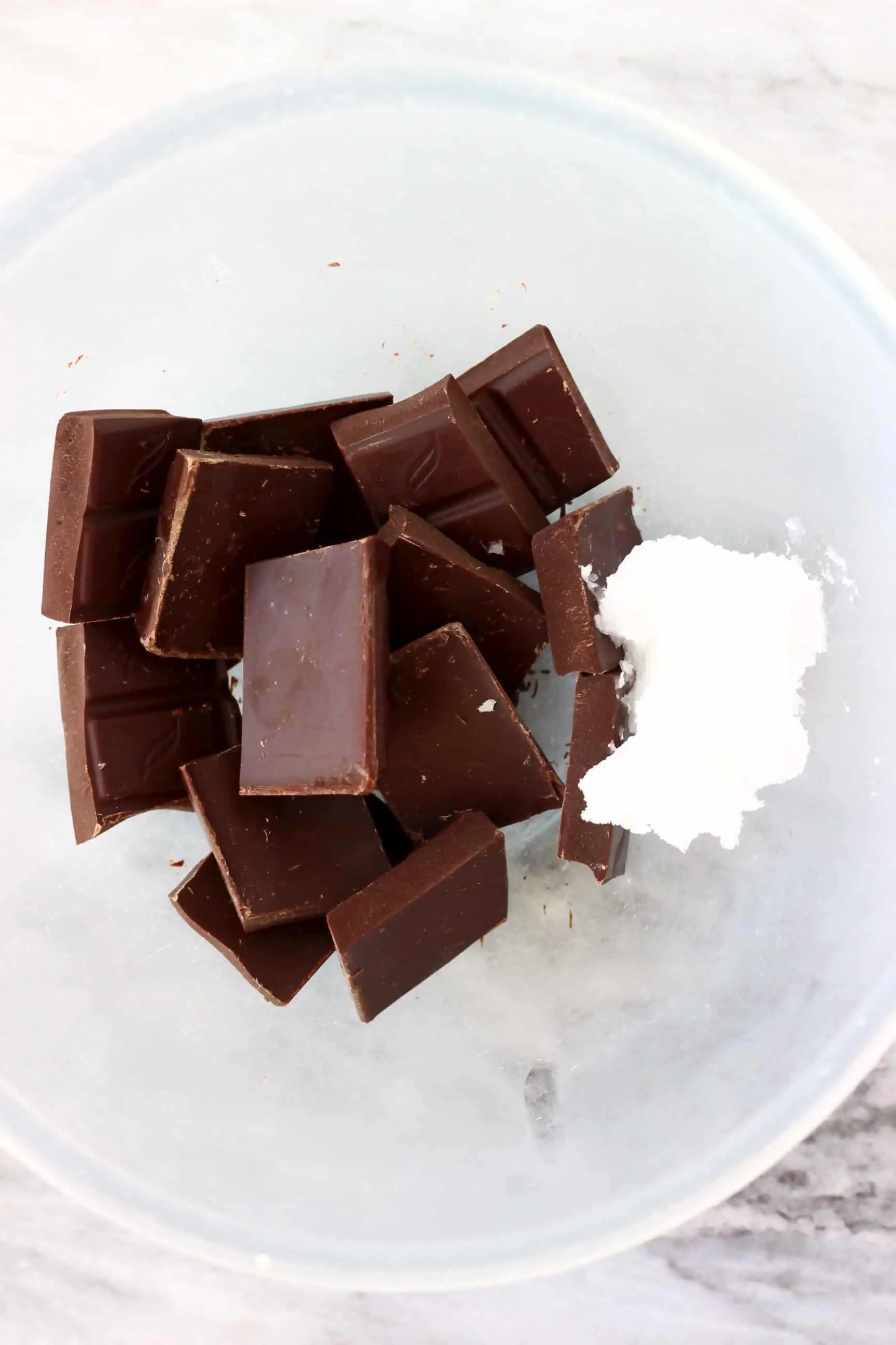 Squares of dark chocolate and coconut oil in a bowl