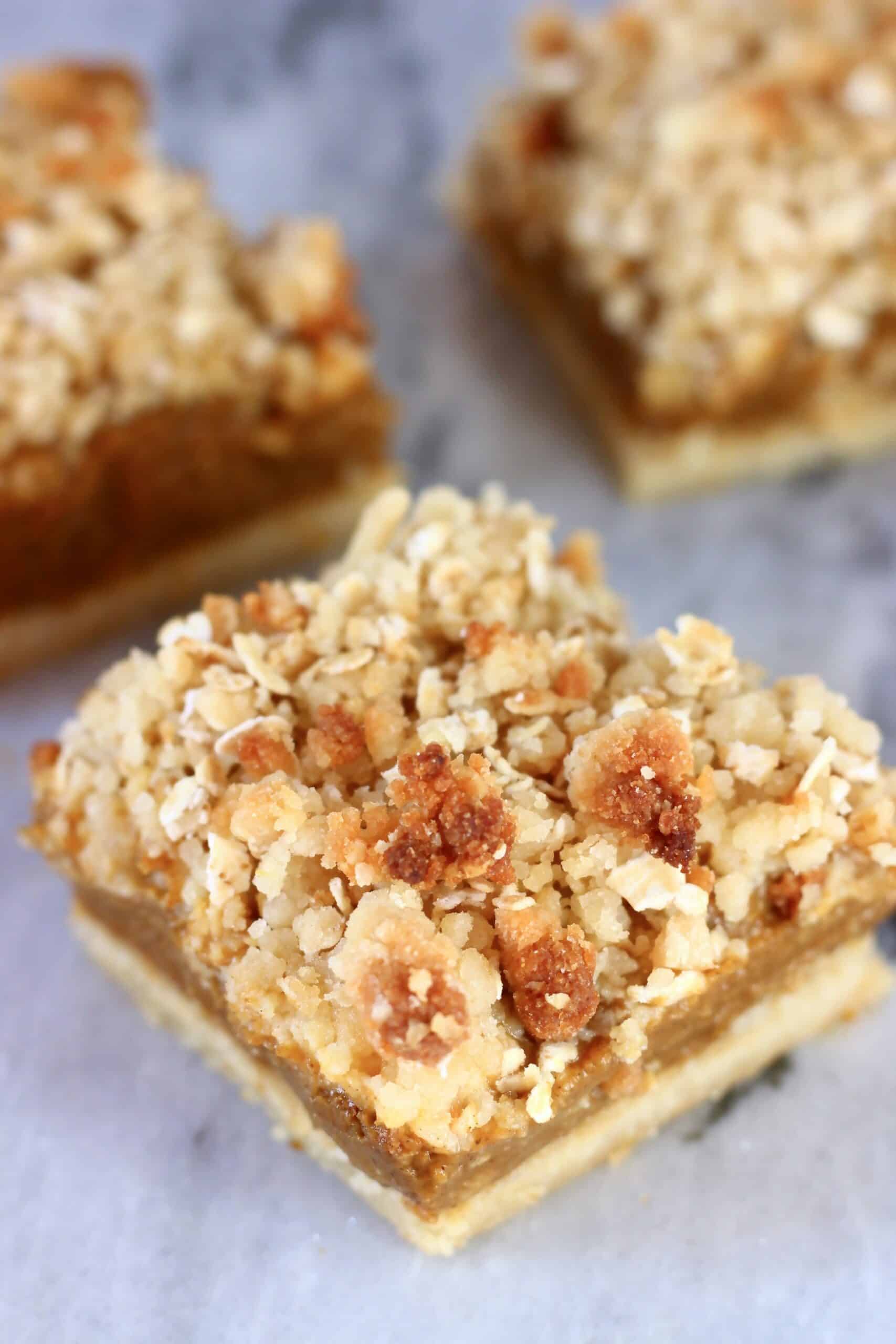 Three vegan pumpkin pie bars with crumble topping