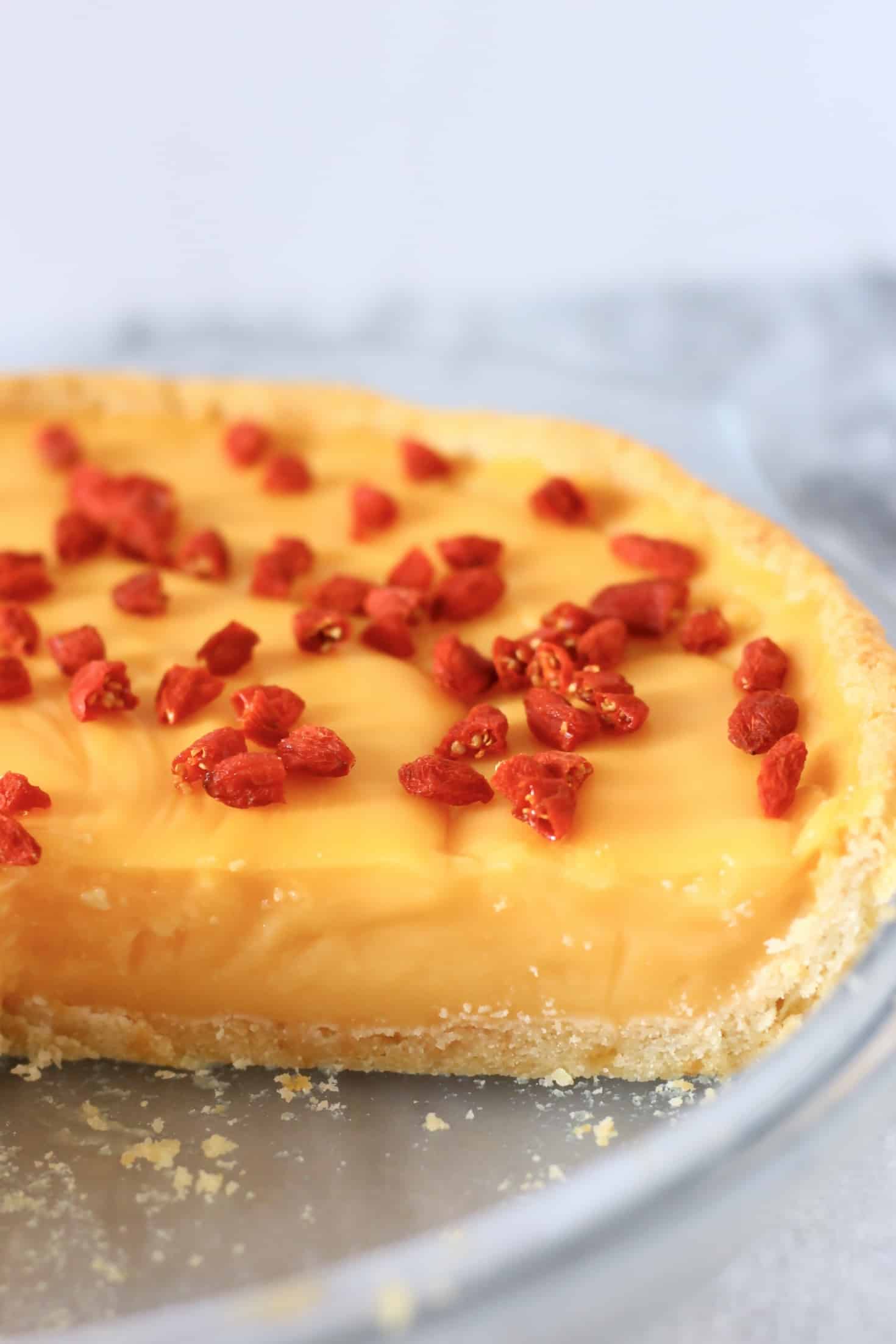 Lemon tart topped with goji berries in a pie dish