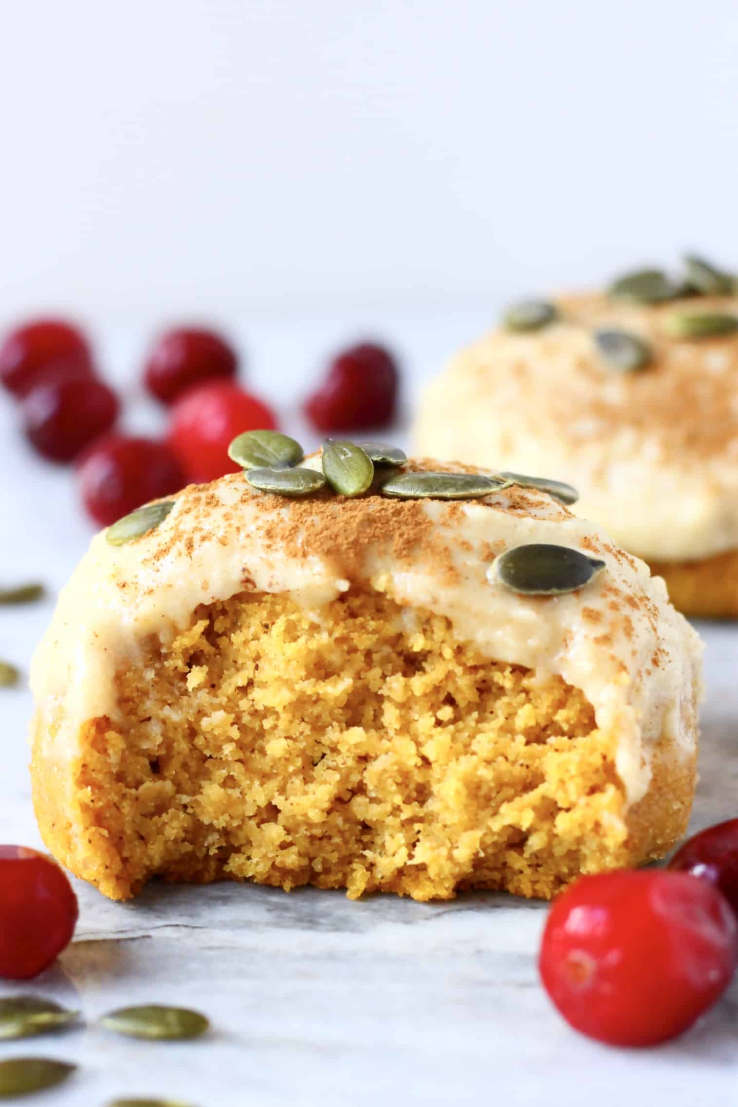 A halved gluten-free vegan pumpkin cookie topped with white frosting and pumpkin seeds