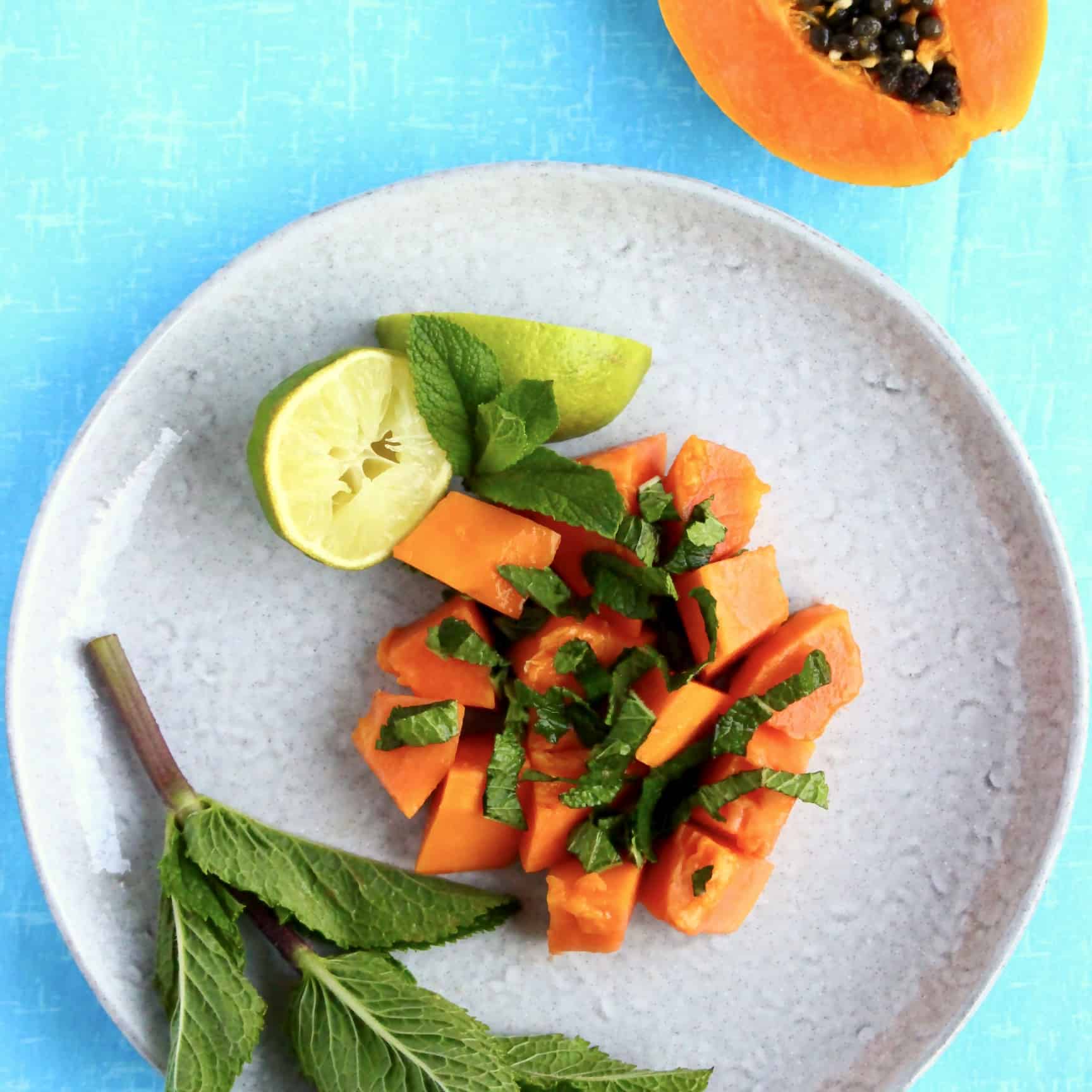 Papaya, lime and mint salad on a grey plate against a blue background