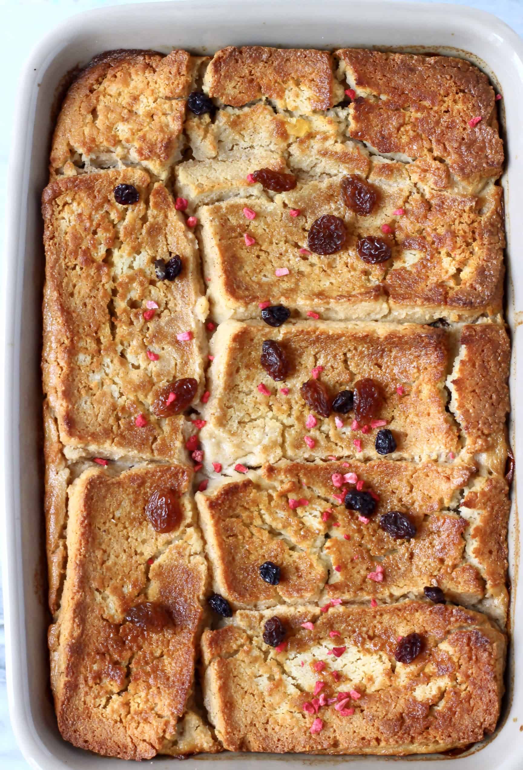 Bread pudding in a grey rectangular baking dish sprinkled with raisins