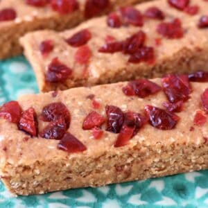 Three vegan protein bars with dried cranberries on a green plate