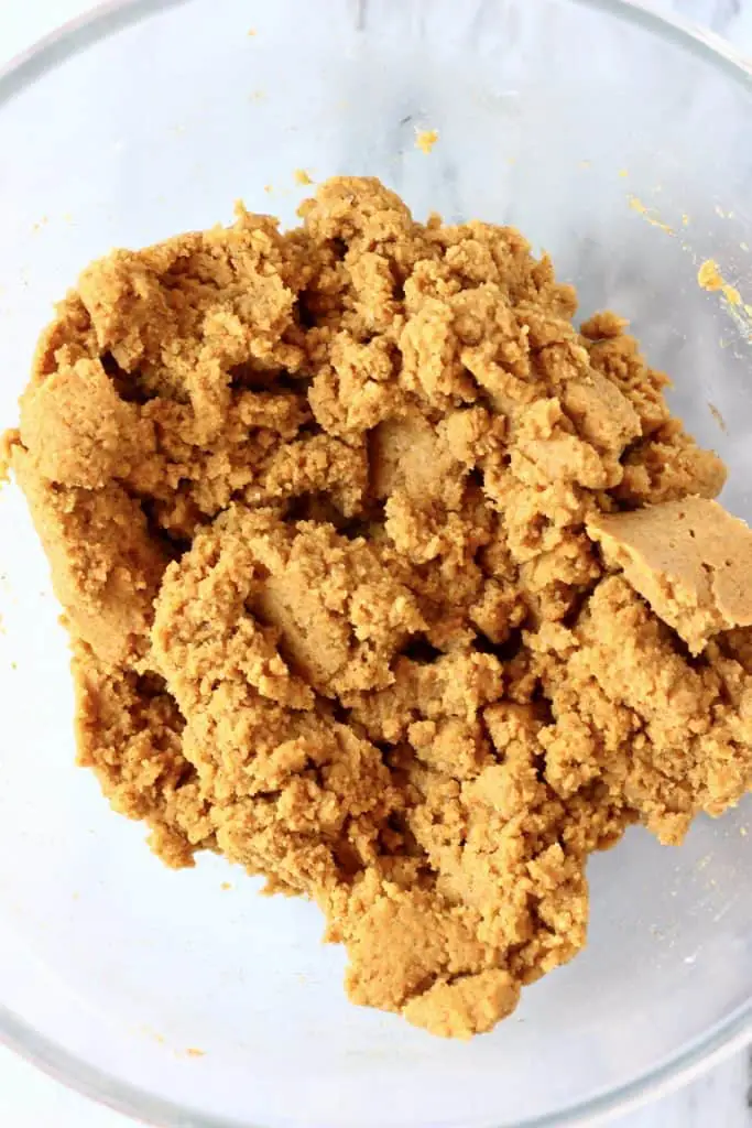 Raw gluten-free vegan pumpkin sugar cookie dough in a glass mixing bowl