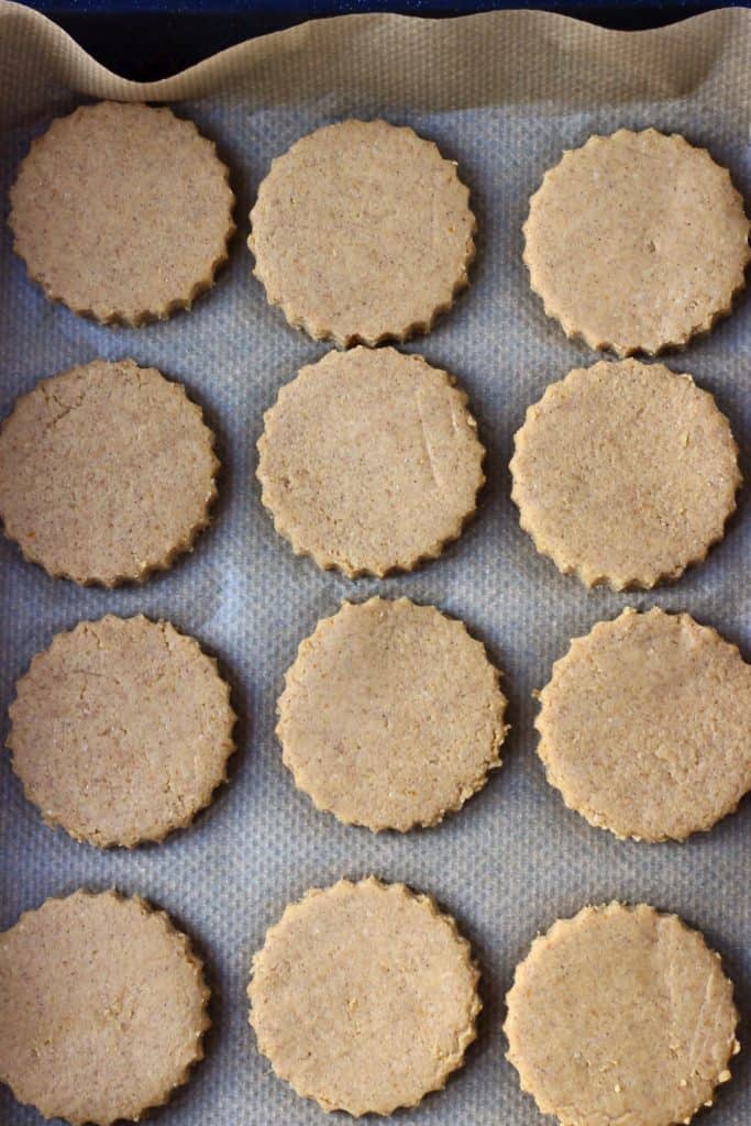 Twelve raw gluten-free vegan pumpkin sugar cookies on a baking tray