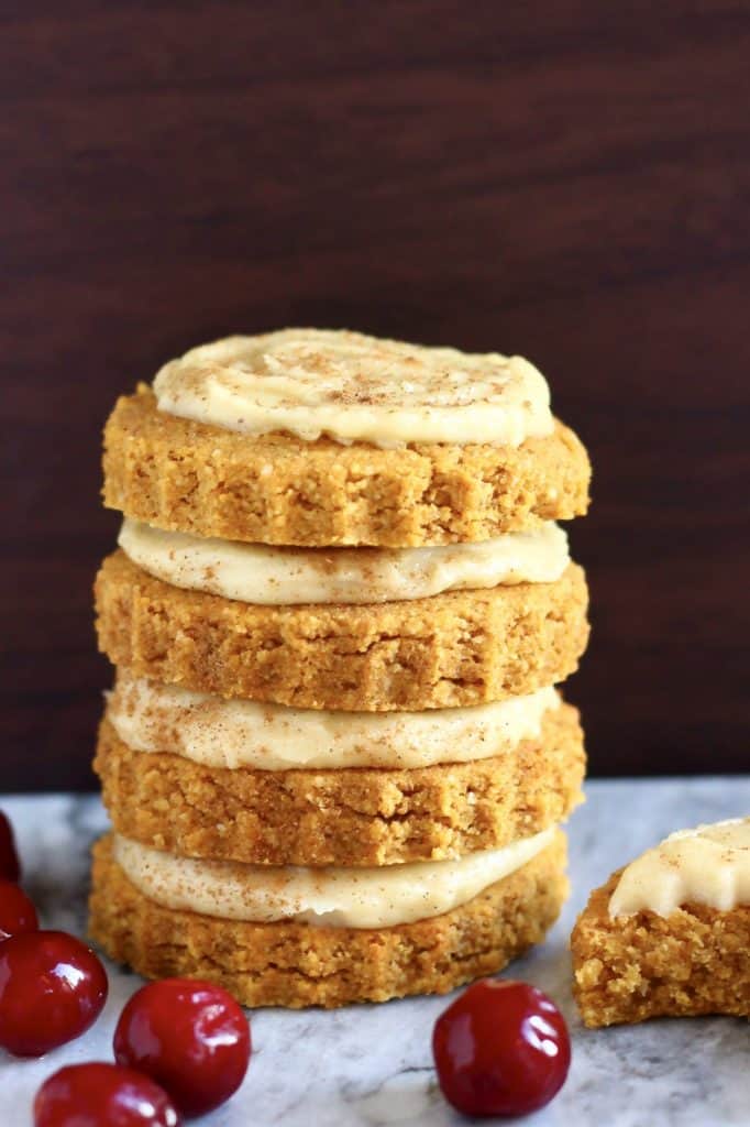 A stack of four gluten-free vegan pumpkin sugar cookies topped with white frosting