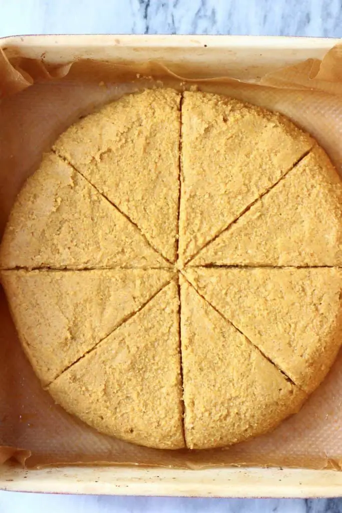 A circle of pumpkin scone dough in a baking tray cut into eight