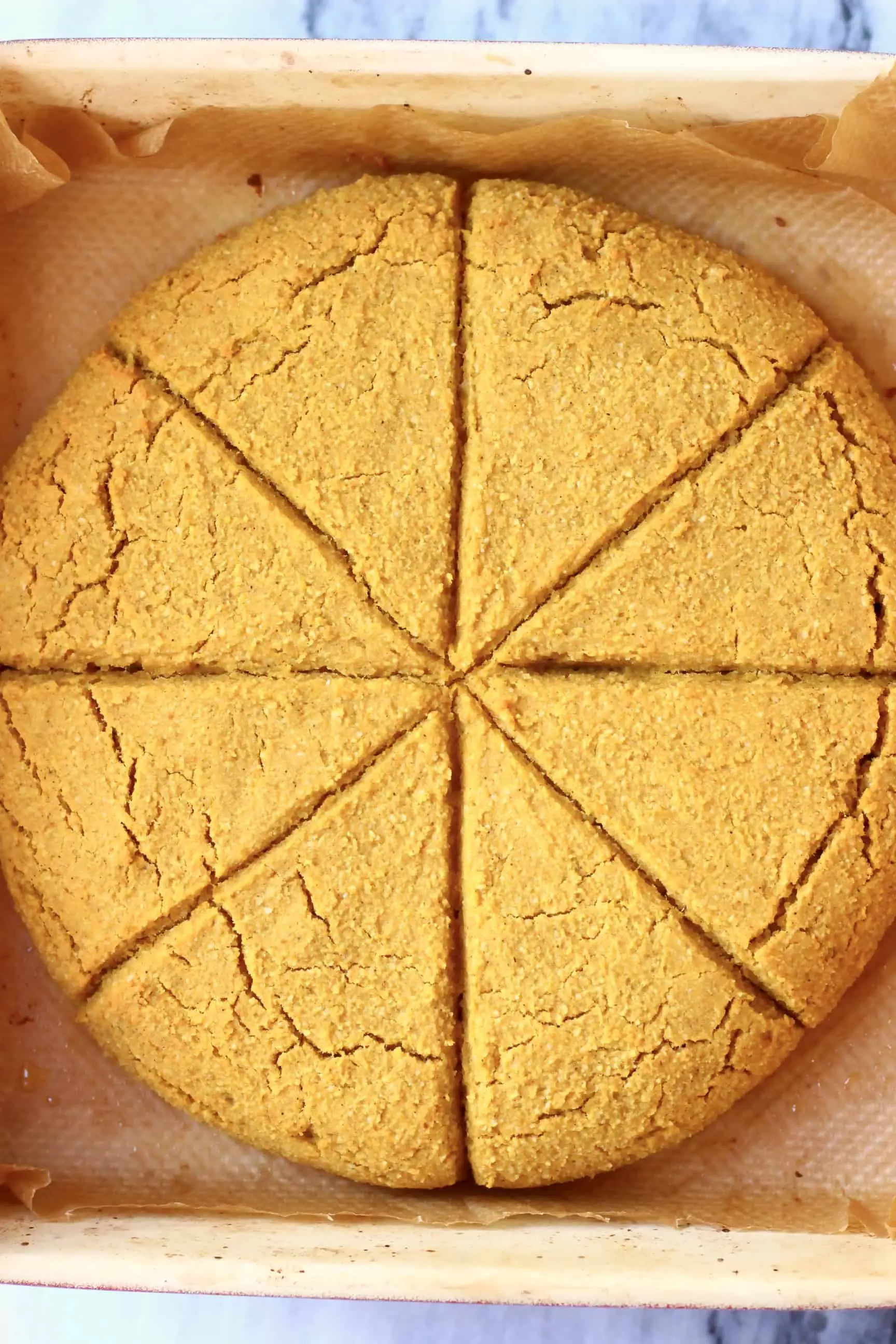 A circle of pumpkin scones in a baking tray cut into eight