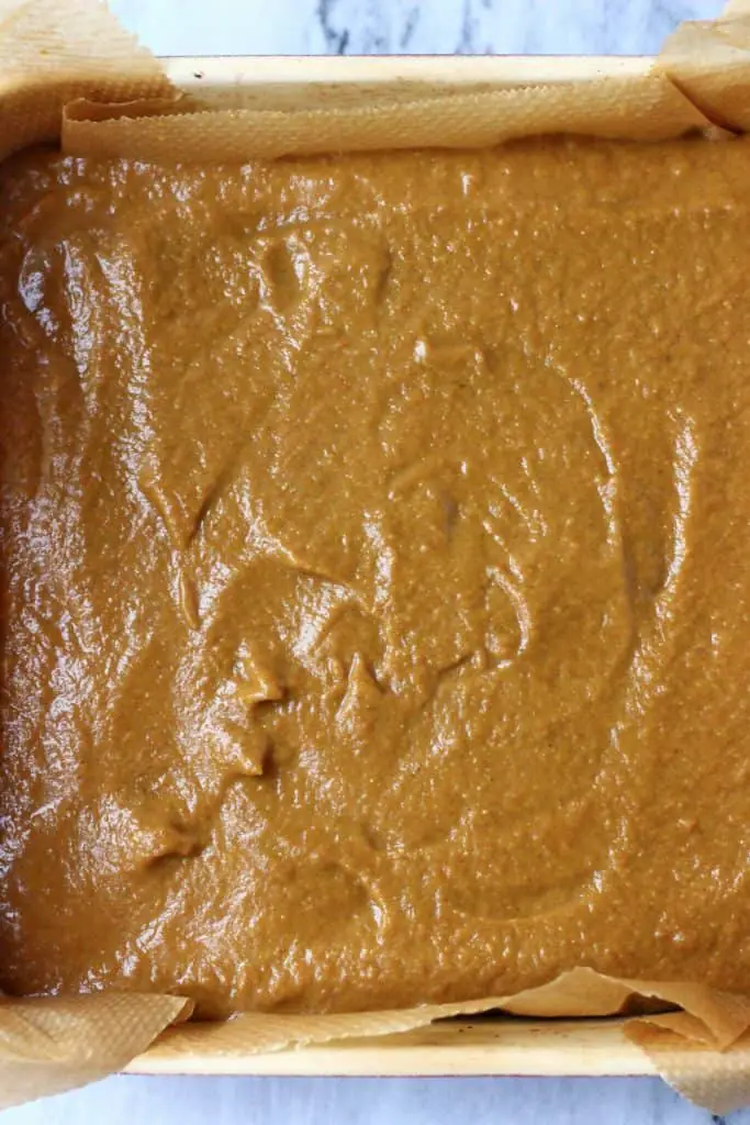 Pumpkin pie filling spread across the bottom of a square baking tin