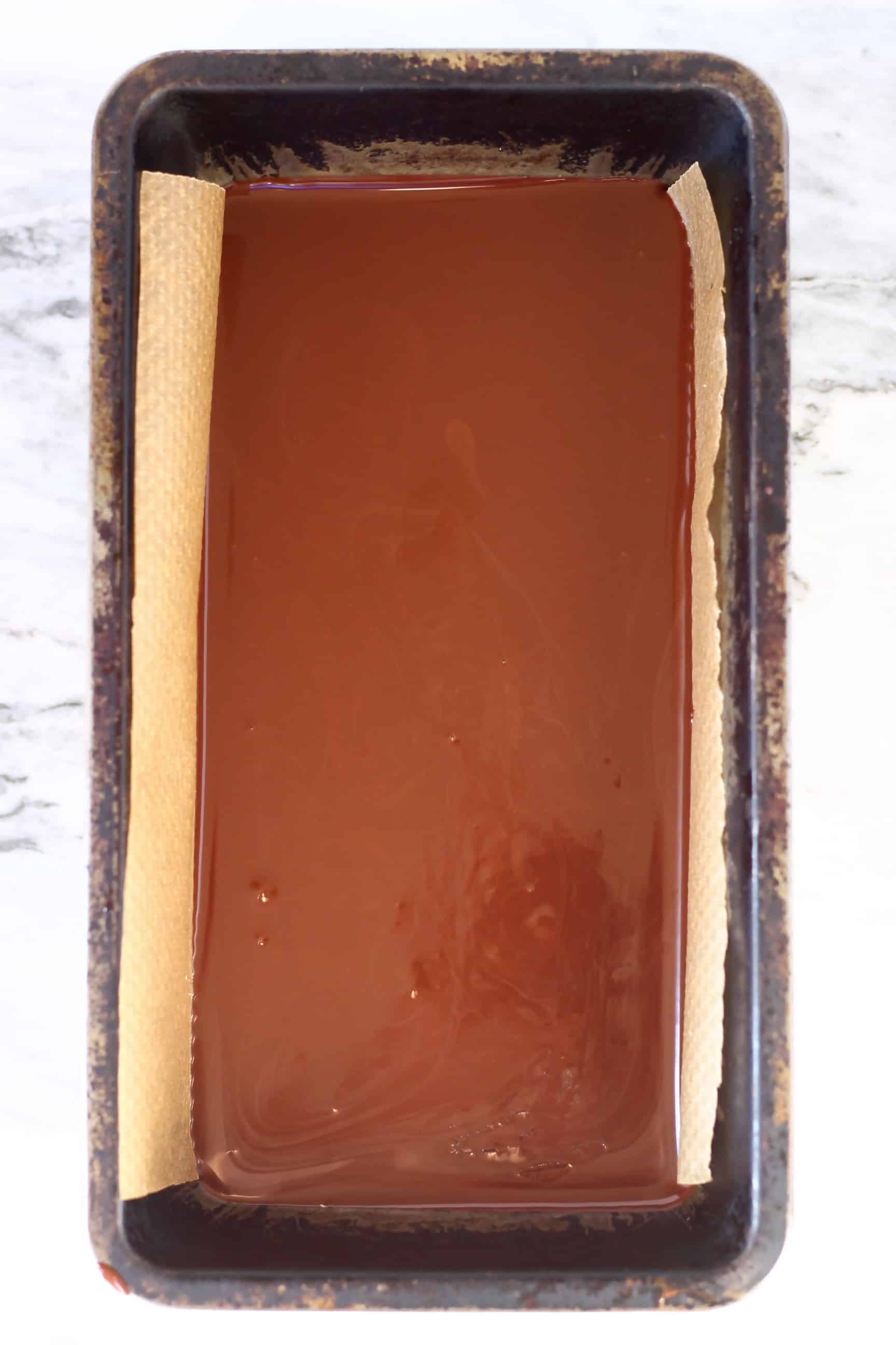Melted chocolate for peanut butter bars in a loaf tin