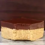 A vegan chocolate peanut butter bar topped with dark chocolate with a bite taken out of it