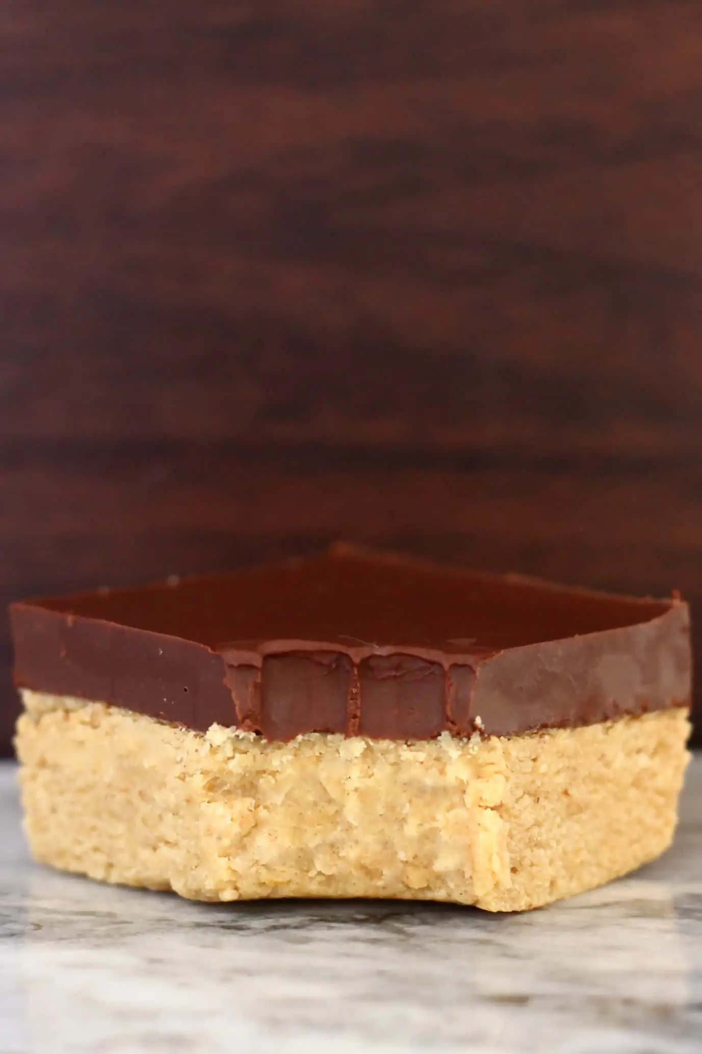 A vegan chocolate peanut butter bar topped with dark chocolate with a bite taken out of it
