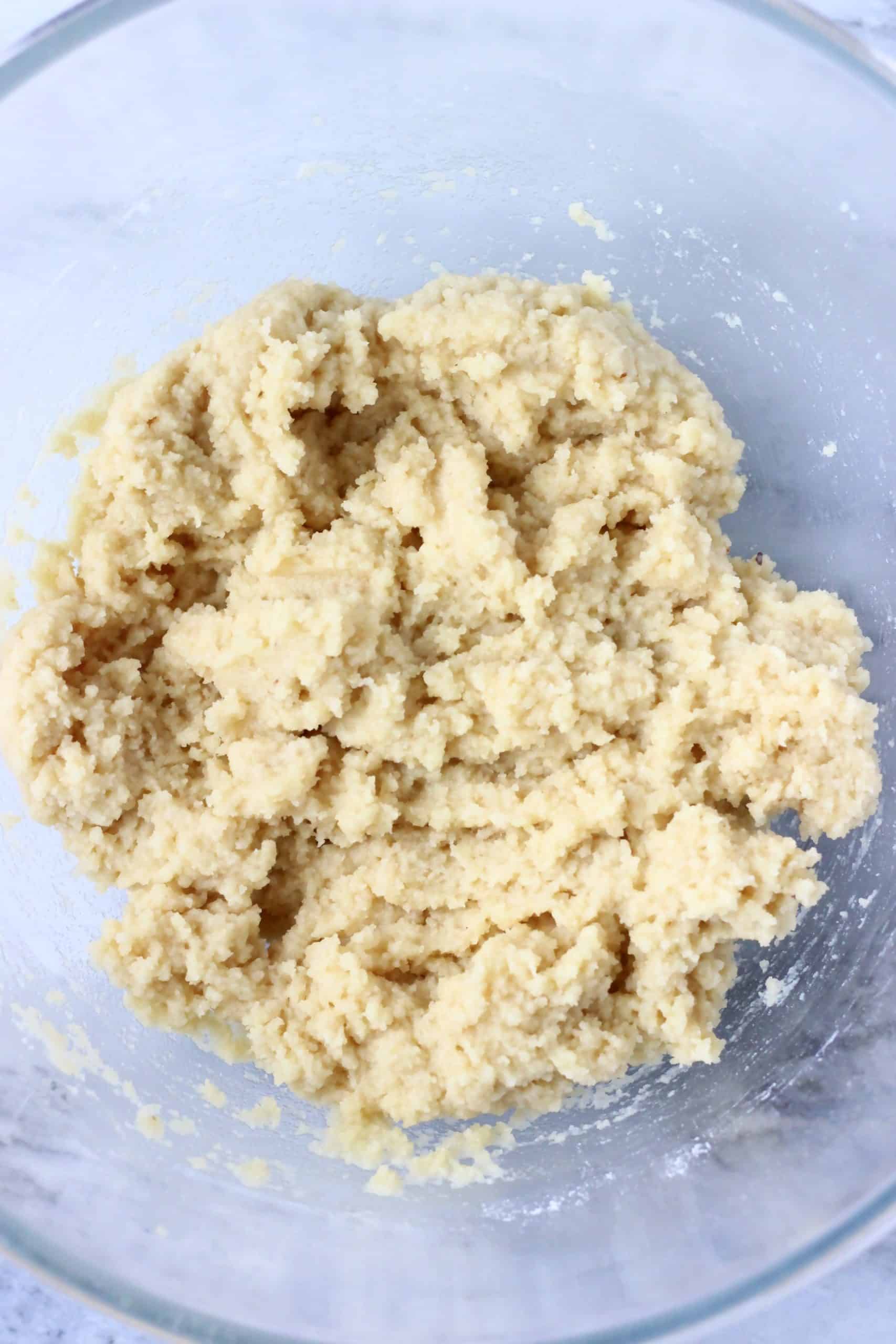 Raw gluten-free vegan lemon cookie dough in a glass mixing bowl