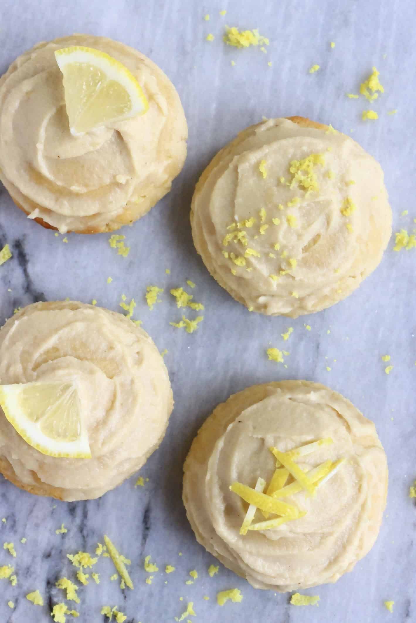 Four gluten-free vegan lemon cookies topped with white frosting and lemon peel