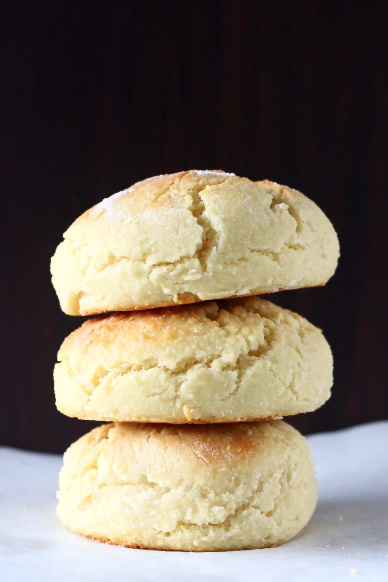Three gluten-free vegan biscuits on top of each other against a dark brown background