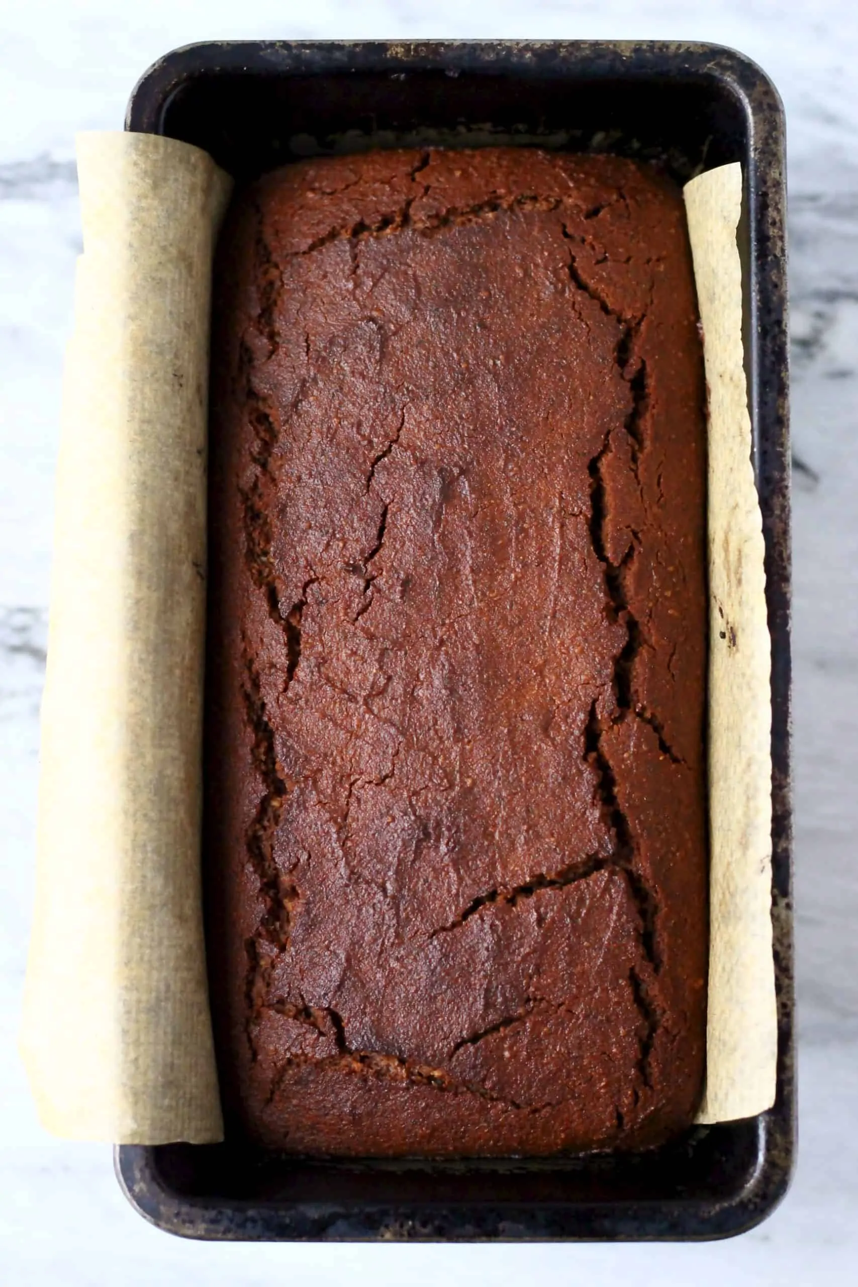 A gluten-free vegan gingerbread loaf cake in a loaf tin lined with baking paper