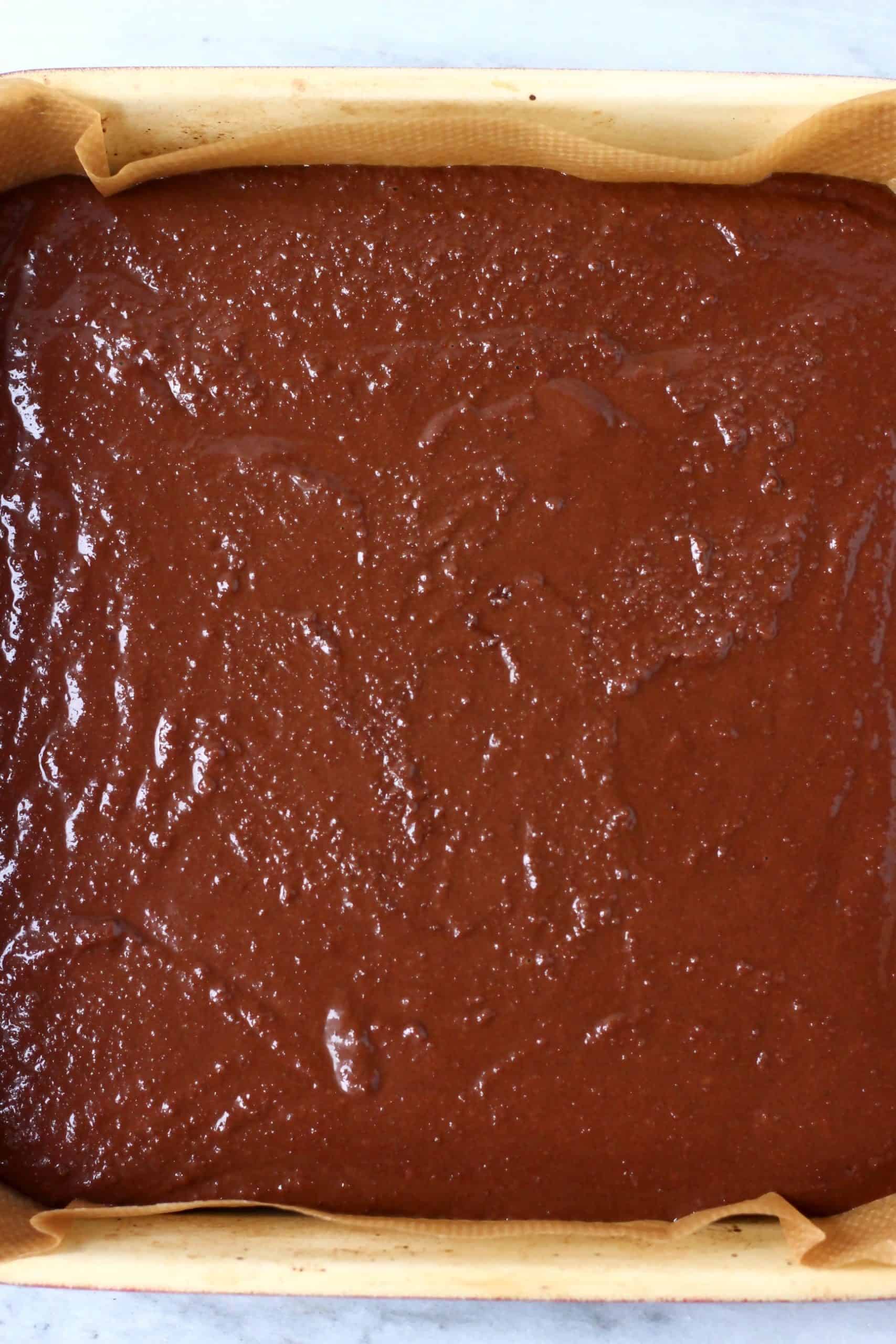 Raw gluten-free vegan yule log batter in a square baking tin lined with baking paper