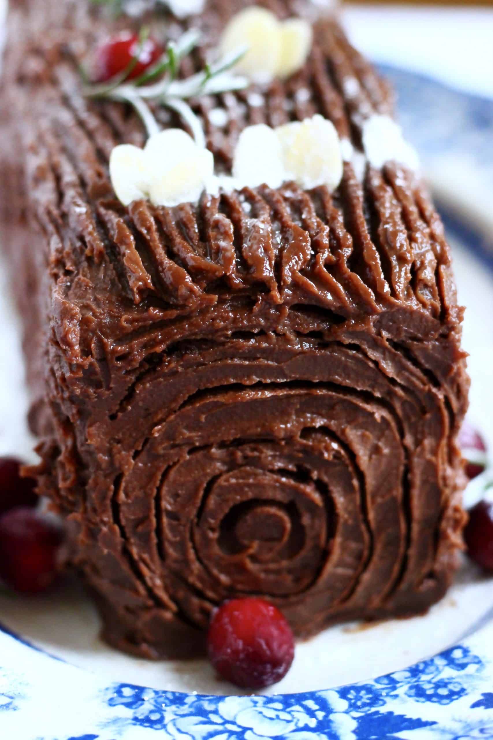 A gluten-free vegan yule log decorated with cranberries, rosemary and flaked almonds