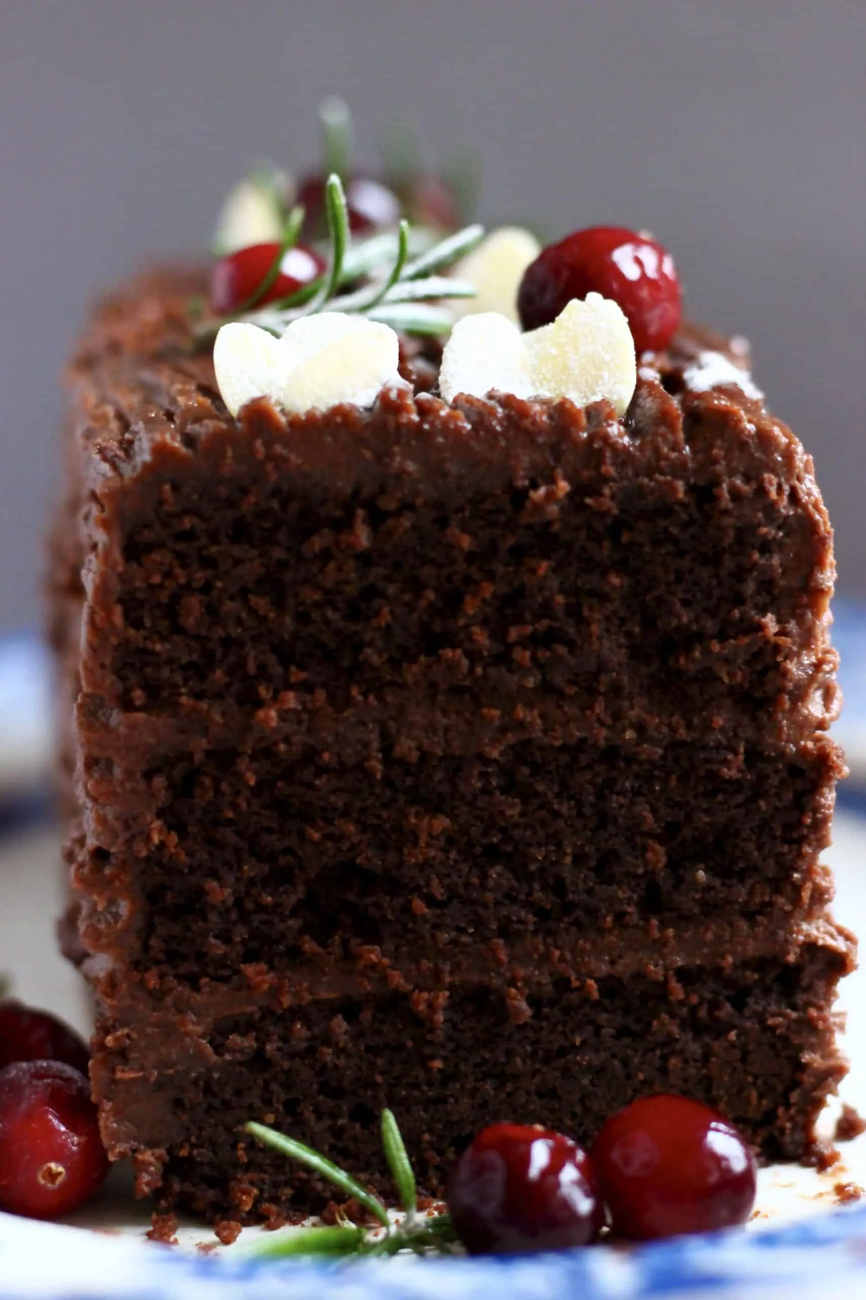 A sliced chocolate yule log with three layers topped with cranberries