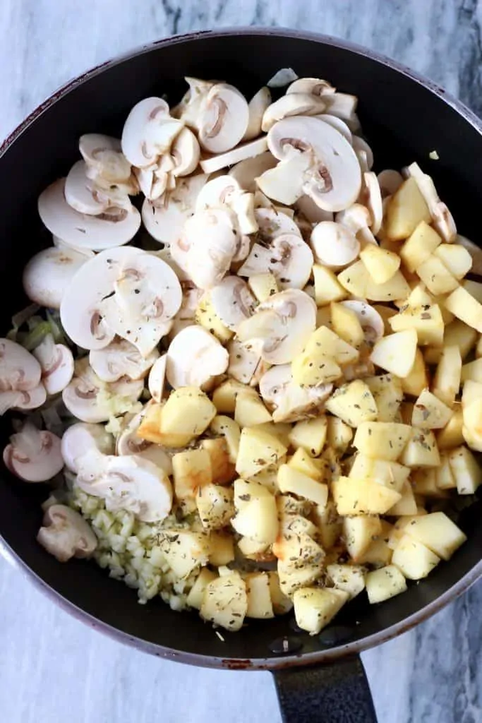 Diced onion, sliced mushrooms and diced apples in a black frying pan