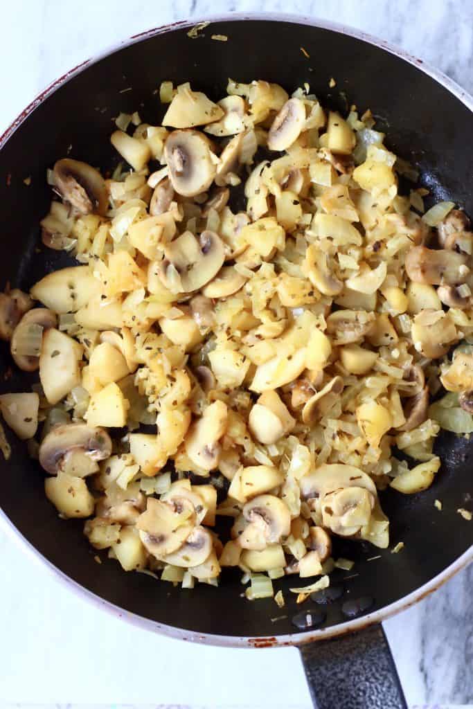 Cooked diced onion, sliced mushrooms and diced apples in a black frying pan