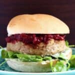 Vegan Christmas burger with cranberry sauce and rocket against a dark brown background