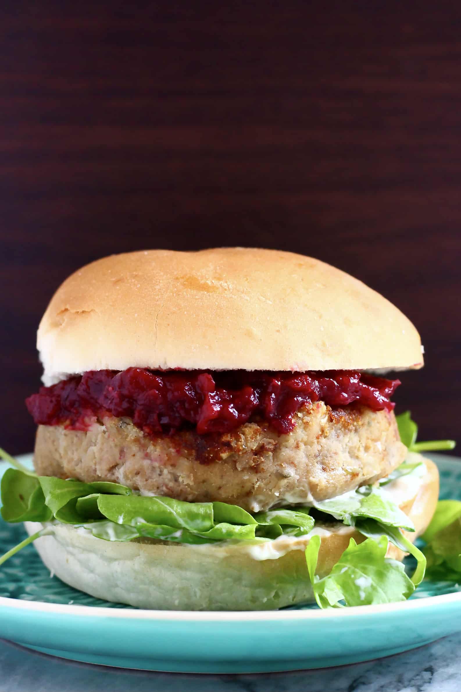 Vegan Christmas burger with cranberry sauce and rocket against a dark brown background