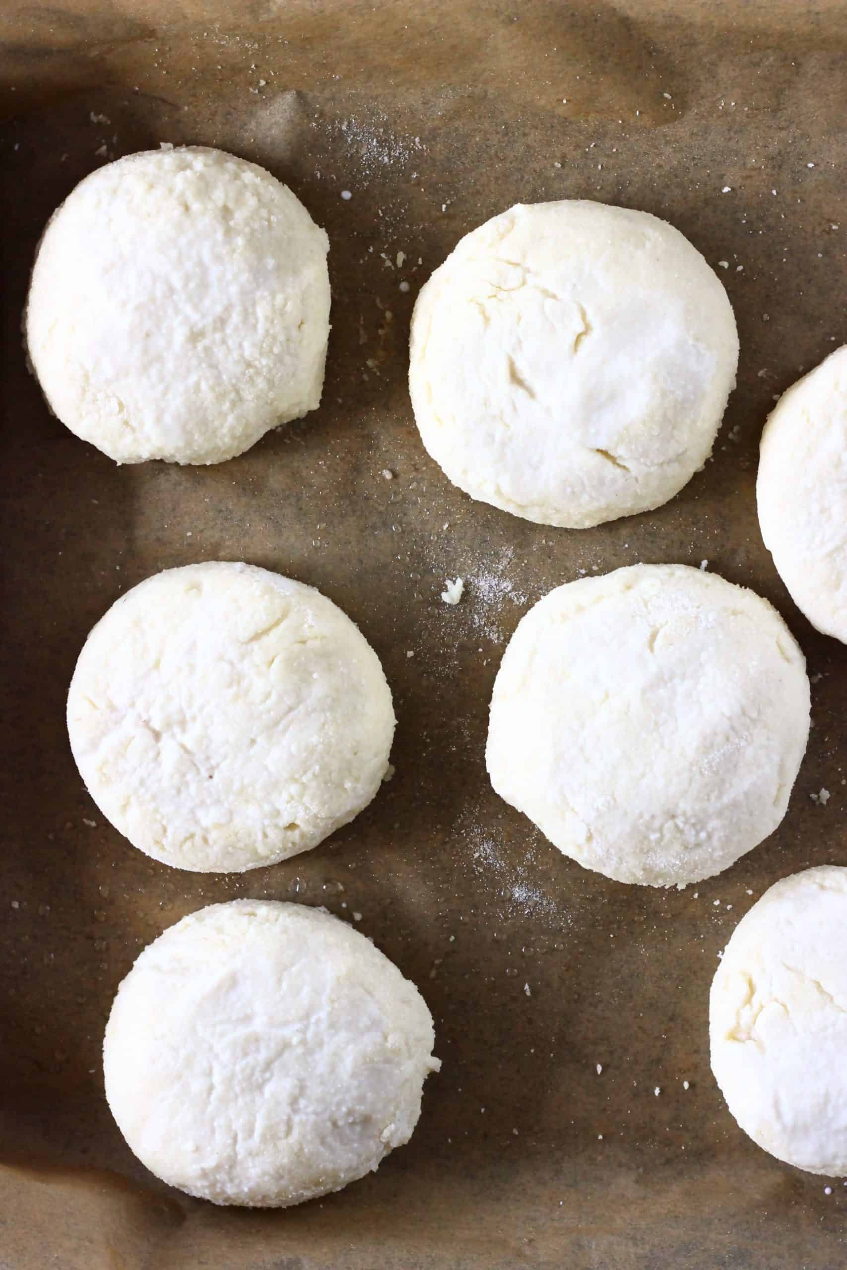 Seven raw gluten-free vegan biscuits on a baking tray