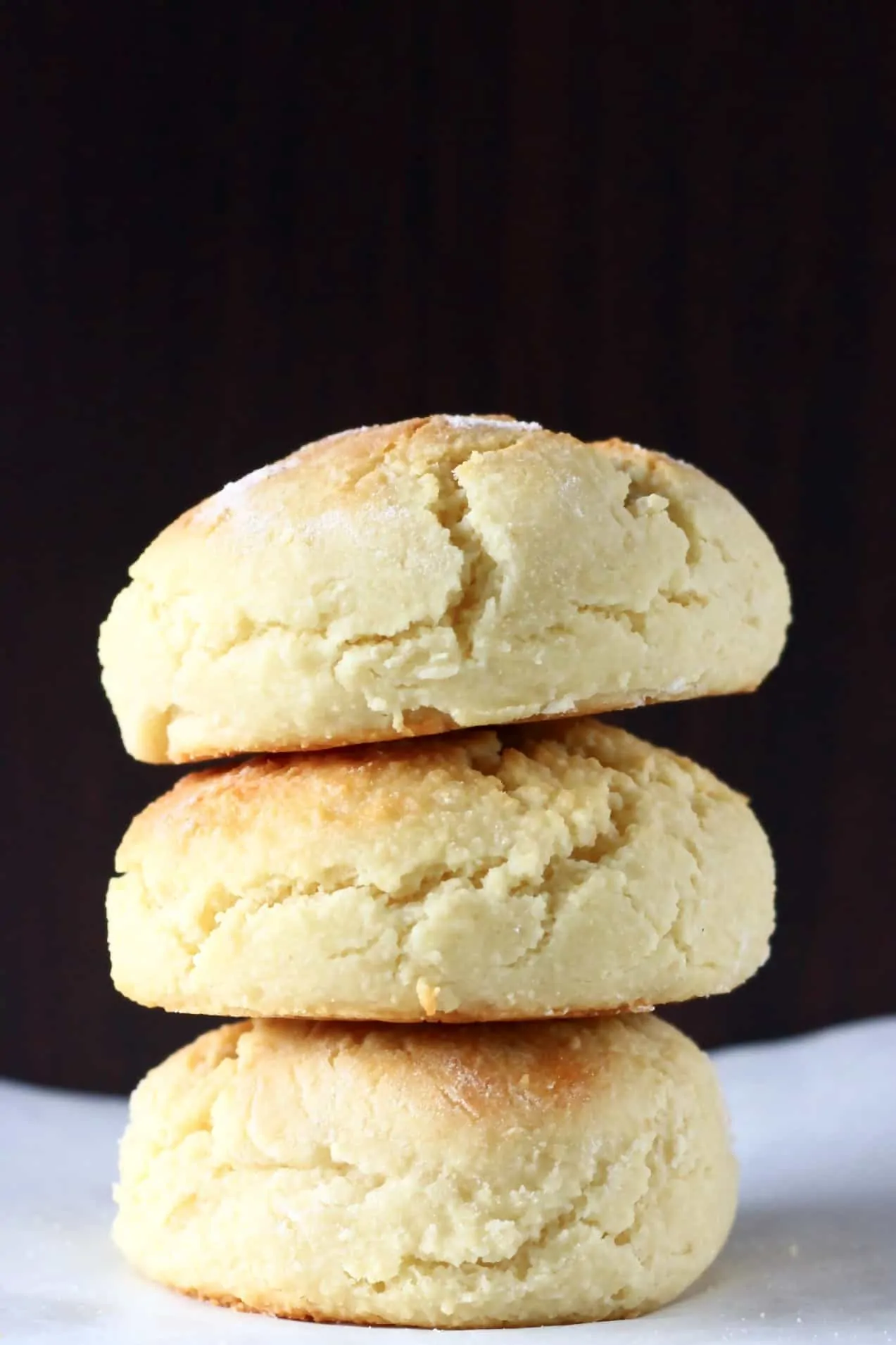 Three gluten-free vegan biscuits stacked on top of each other against a dark brown background
