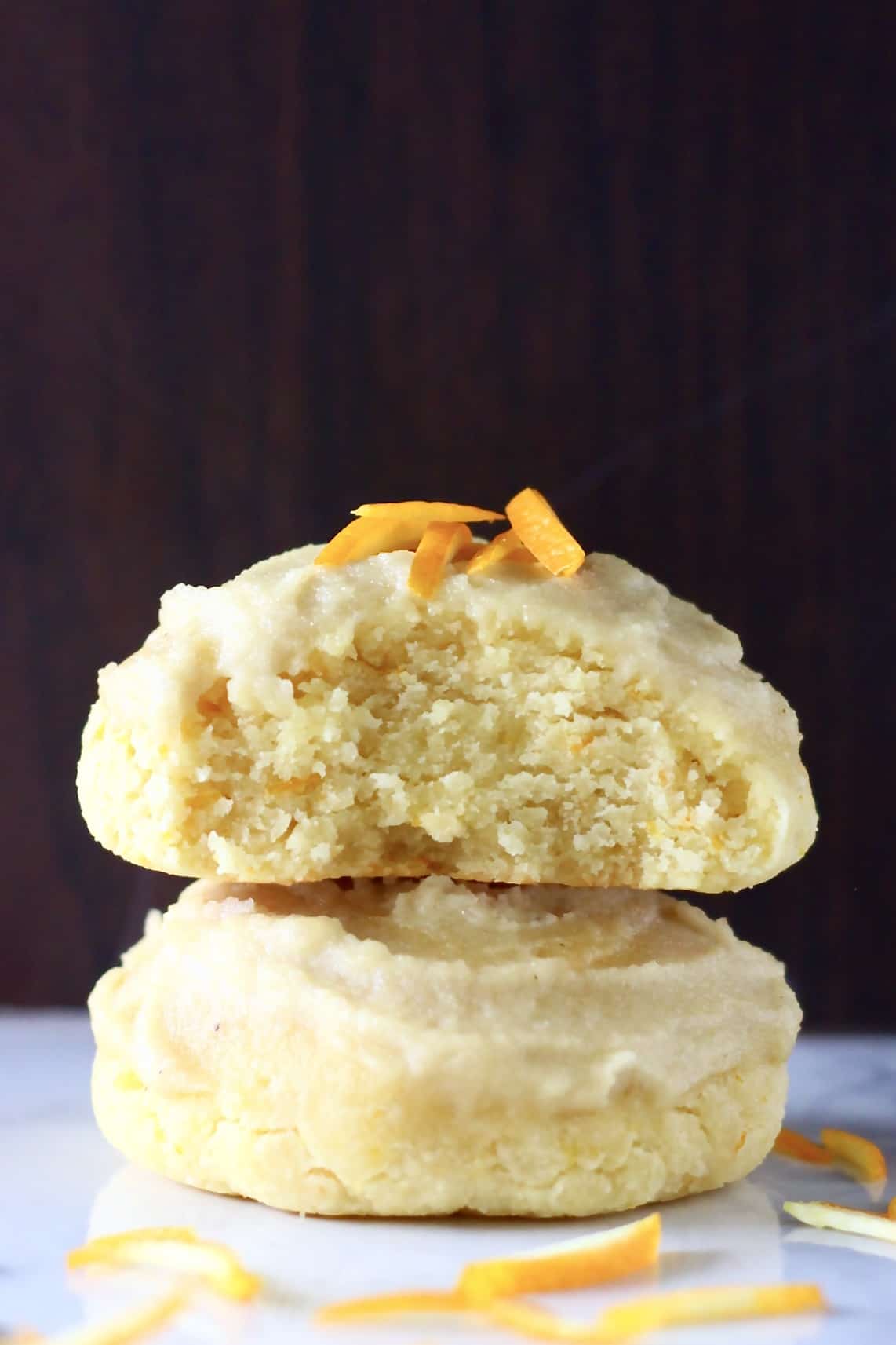 Two gluten-free vegan orange cookies stacked on top of each other, one with a bite taken out