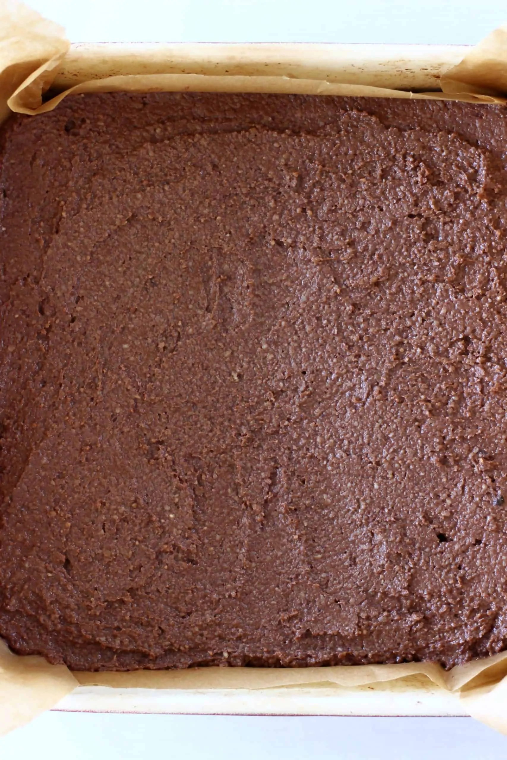 Raw vegan peppermint brownie batter in a square baking tin lined with baking paper